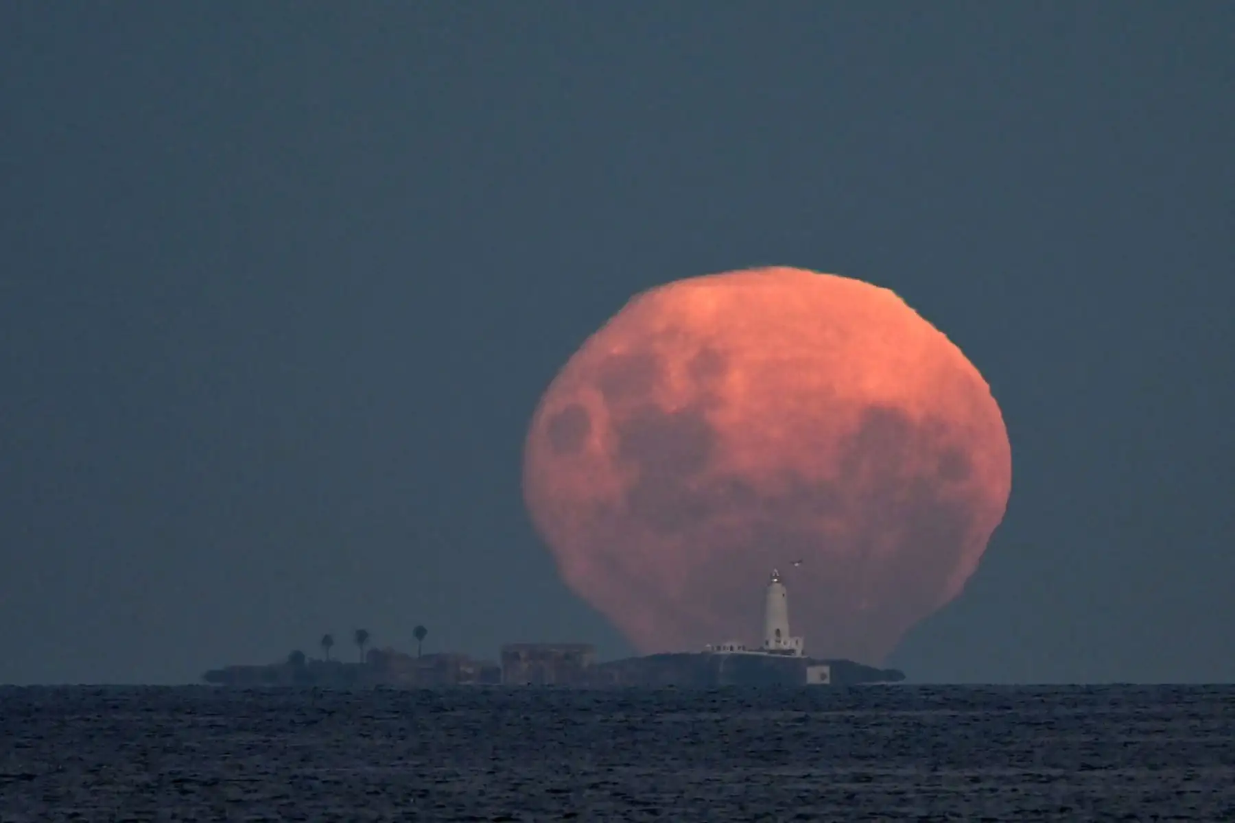 La luna en fase gibosa menguante se eleva tras la isla de Flores, frente a la costa de Montevideo. Foto: ANDINA/AFP