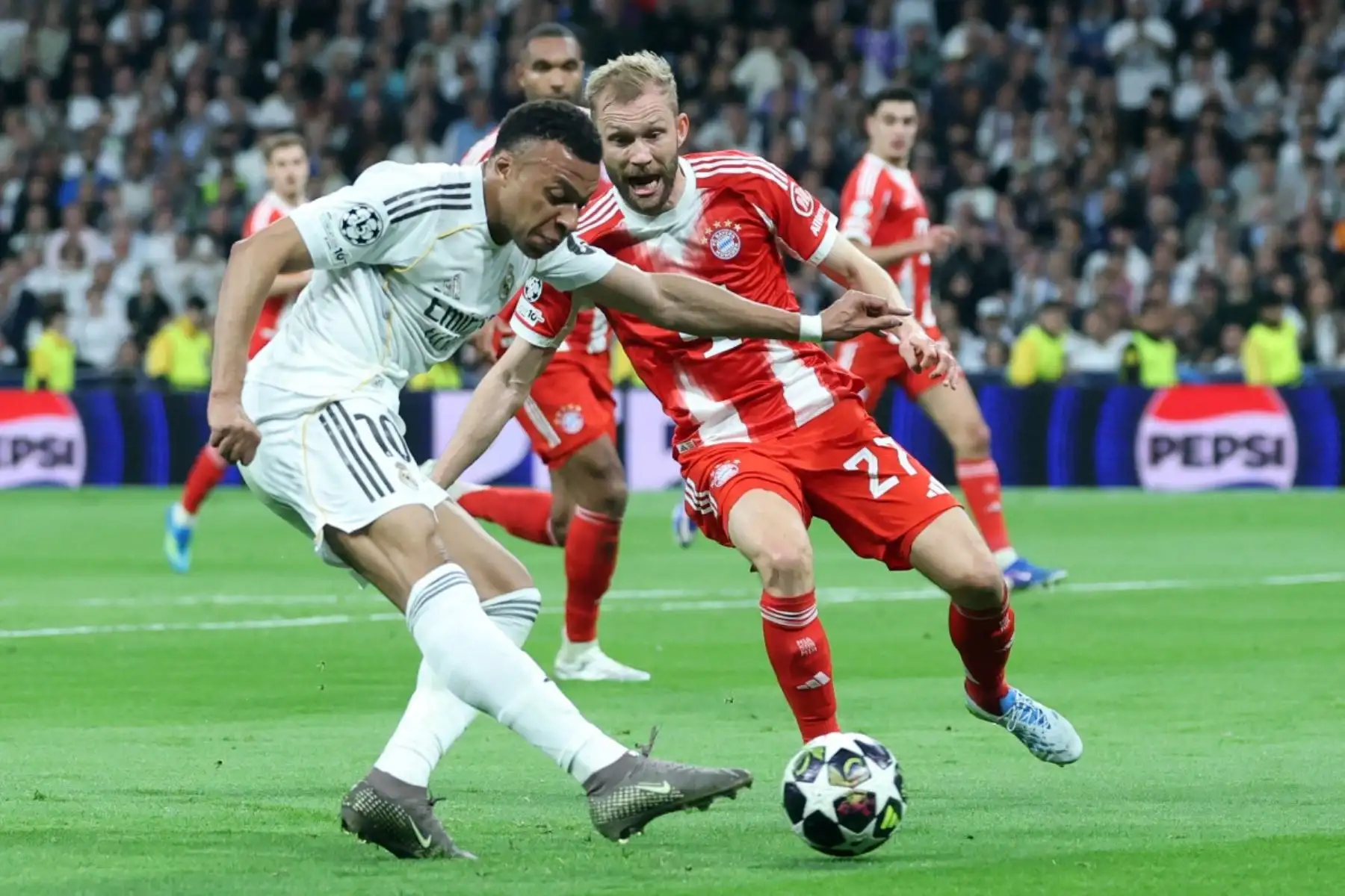 El delantero francés del Real Madrid, Kylian Mbappé , dispara a puerta mientras el centrocampista austriaco del Bayern de Múnich, Konrad Laimer  lo detiene durante el partido de ida de los cuartos de final de la UEFA Champions League entre el Real Madrid CF y el FC Bayern de Múnich. AFP