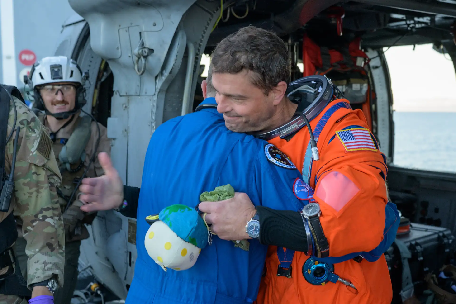El astronauta de la NASA Reid Wiseman, comandante de la misión Artemis II, abraza al cirujano de vuelo de la NASA Richard Scheuring junto a un helicóptero MH-60 Seahawk de la Armada, perteneciente al Escuadrón de Combate Marítimo de Helicópteros (HSC) 23, en la cubierta de vuelo del USS John P. Murtha. Crédito de la imagen: NASA/Bill Ingalls