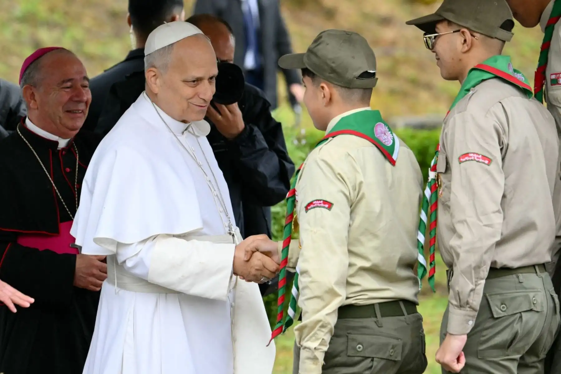El papa León XIV estrecha la mano de unos scouts antes de plantar un olivo durante una visita al yacimiento arqueológico de Hippo, en Annaba. Foto: AFP