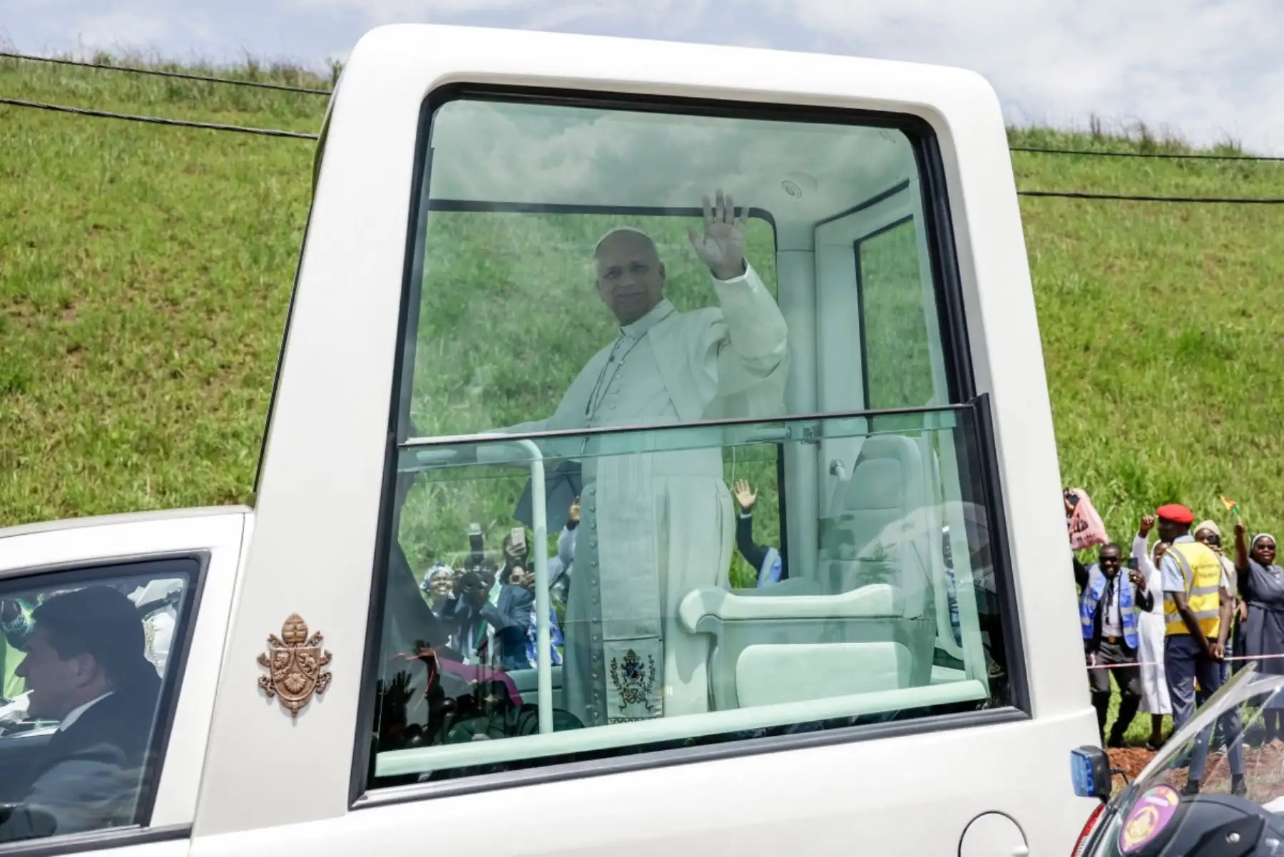 El Papa León XIV (izq.) saluda a sus seguidores desde el papamóvil mientras se dirige a la Catedral de San José en Bamenda, en el cuarto día de un viaje apostólico de 11 días a África