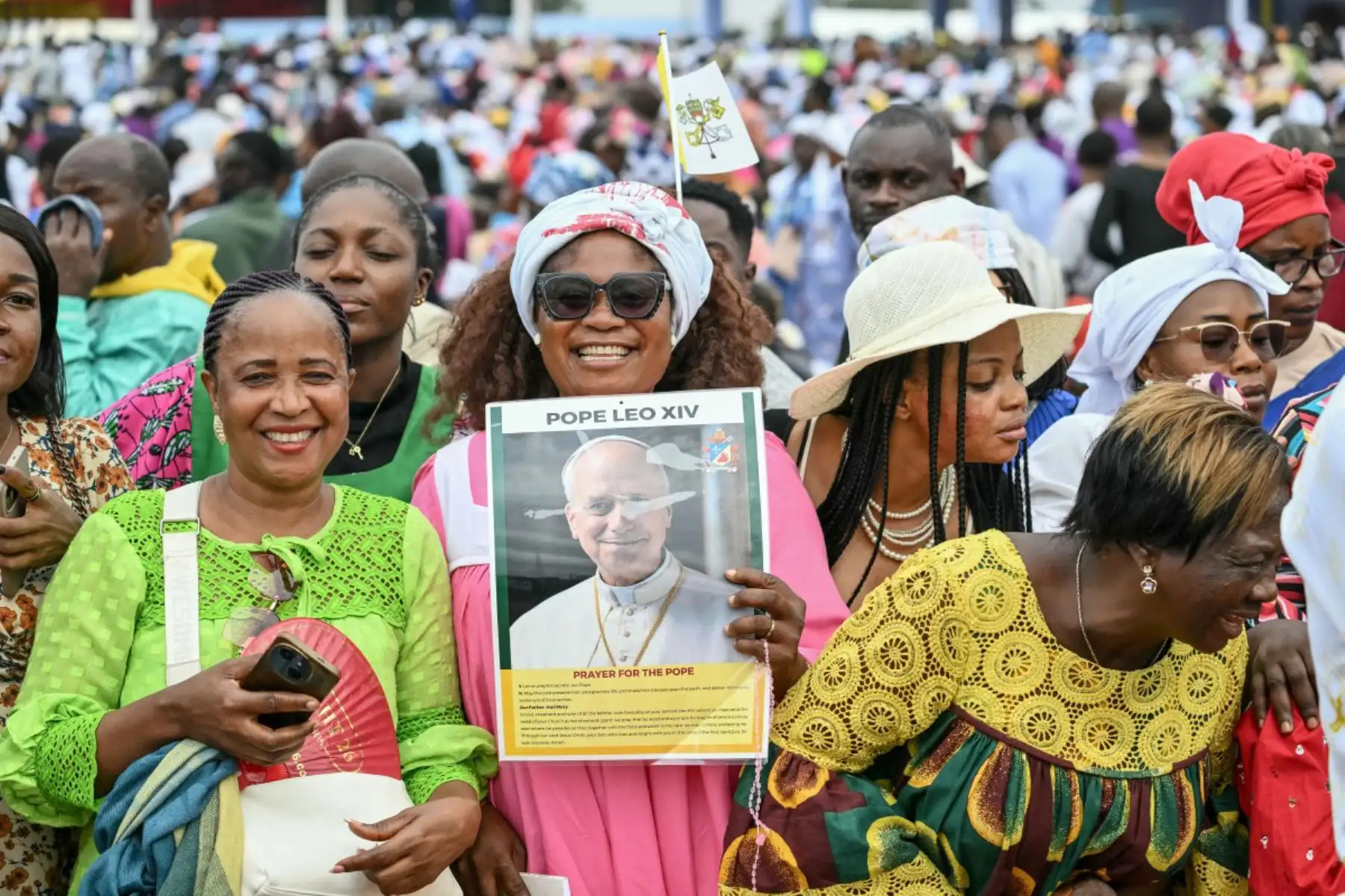 Una fiel sostiene un cartel del Papa León XIV mientras se reúne con otras personas para esperar su llegada para oficiar la Santa Misa en el aeropuerto de Yaoundé Ville, en Yaoundé, el sexto día de un viaje apostólico de 11 días a África. Foto: ANDINA/AFP