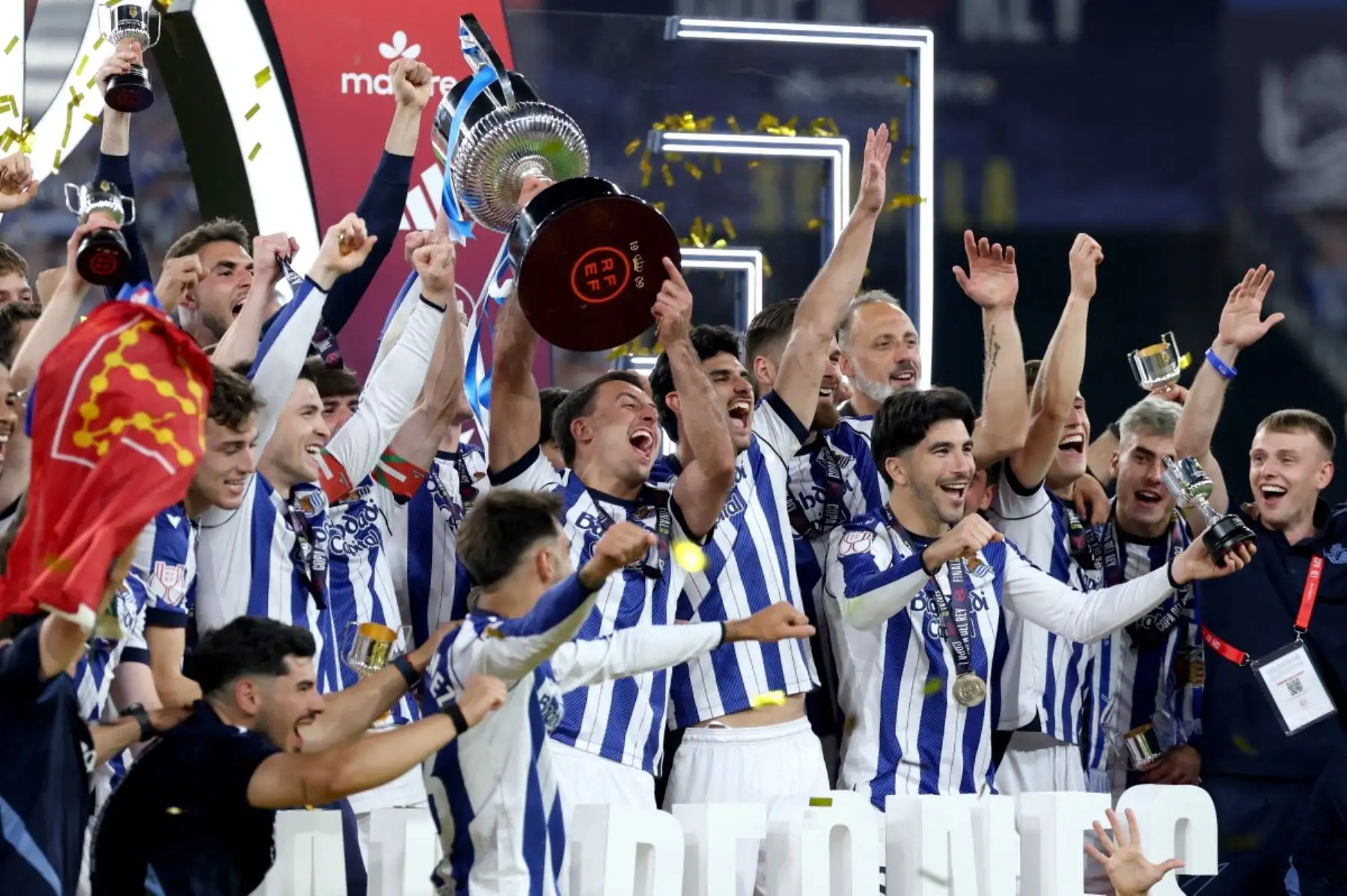 El delantero español #10 de la Real Sociedad, Mikel Oyarzabal (C), y sus compañeros de equipo celebran con el trofeo al final del partido final de fútbol de la Copa del Rey (Copa del Rey) entre el Club Atlético de Madrid y la Real Sociedad en el estadio La Cartuja de Sevilla el 18 de abril de 2026. La Real Sociedad venció al Atlético de Madrid 4-3 en los penaltis. (Foto de Thomas COEX / AFP)