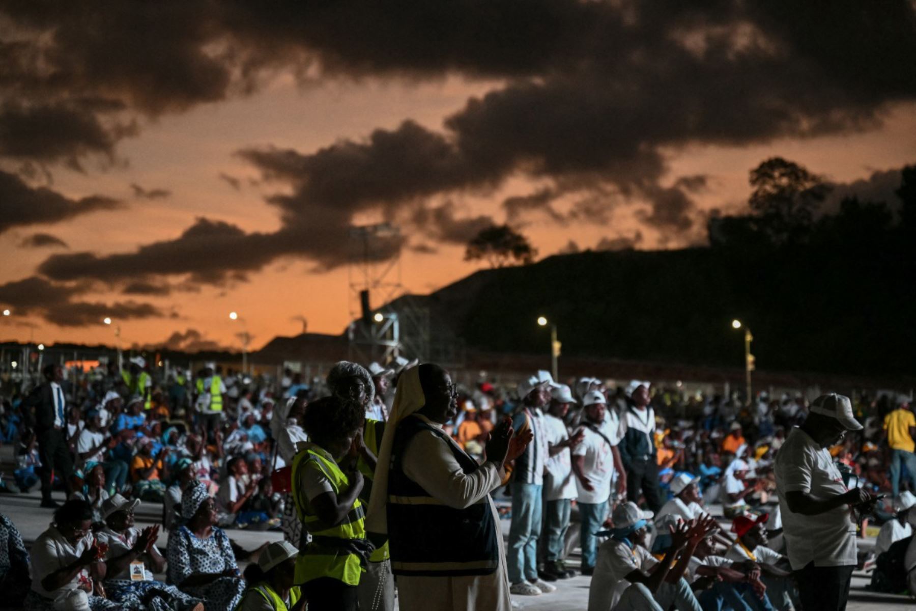 Fieles asisten al rezo del Santo Rosario, dirigido por el Papa León XIV, en la explanada frente al santuario de "Mama Muxima" en Muxima, en el séptimo día de una gira apostólica de 11 días por África. Foto: ANDINA/AFP