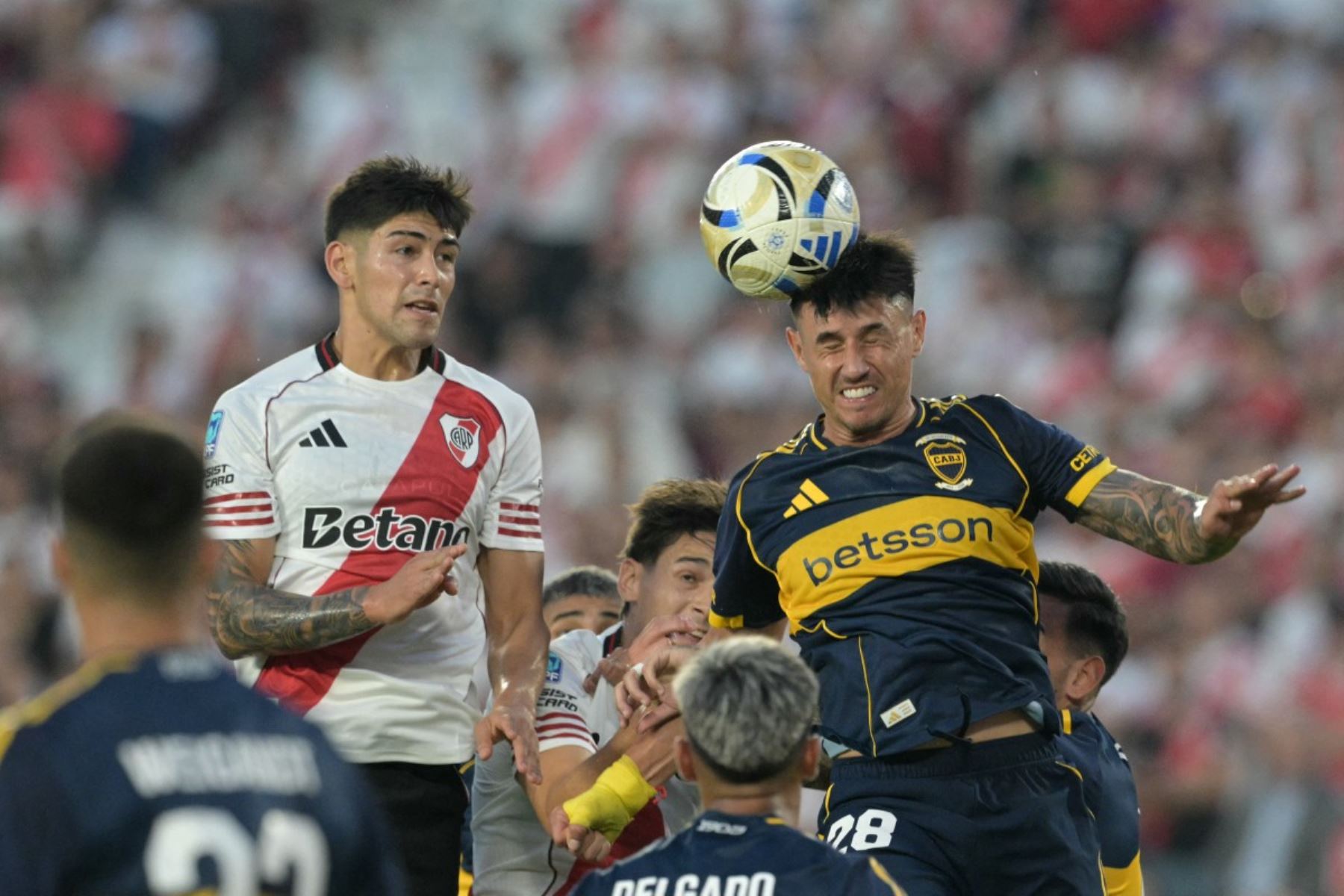 El delantero paraguayo Adam Bareiro (derecha), número 28 del Boca Juniors, cabecea el balón superando al defensor Lautaro Rivero (izquierda), número 13 del River Plate, durante el partido del Torneo Apertura 2026 de la Liga Argentina de Fútbol Profesional entre River Plate y Boca Juniors en el estadio MAS Monumental de Buenos Aires, el 19 de abril de 2026. (Foto de JUAN MABROMATA / AFP)