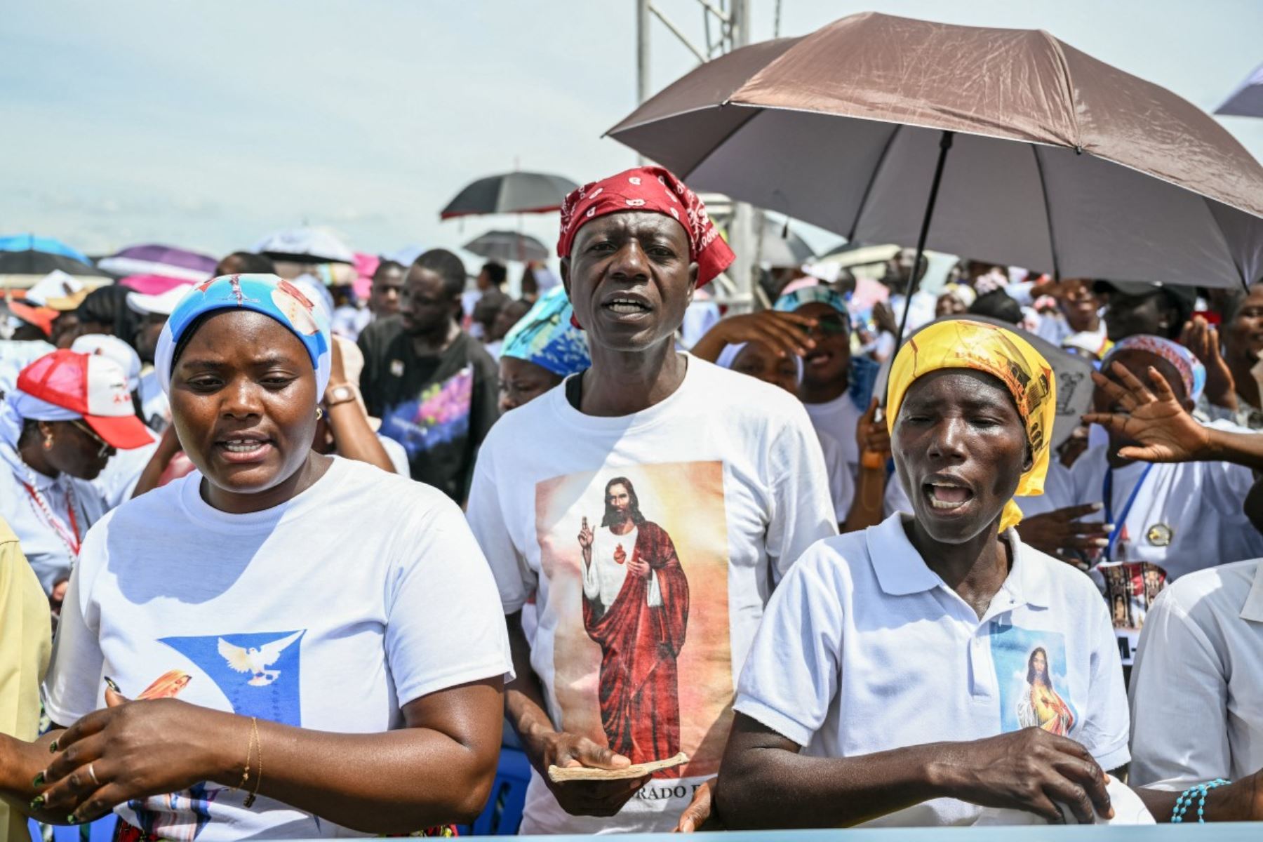 Fieles cantan mientras se congregan antes de la Santa Misa del Papa León XIV en la explanada de Saurimo, en el octavo día de un viaje apostólico de 11 días a África. Foto: AFP