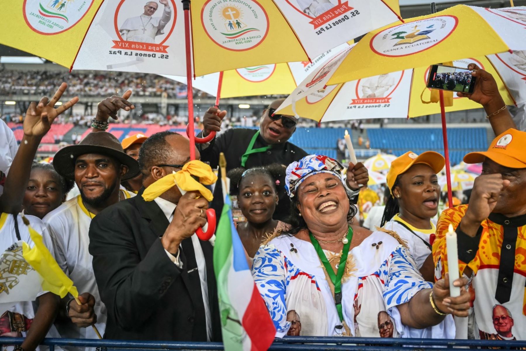 Los fieles ondean banderas y sostienen paraguas al recibir al Papa León XIV para un encuentro con jóvenes y familias. Foto: AFP