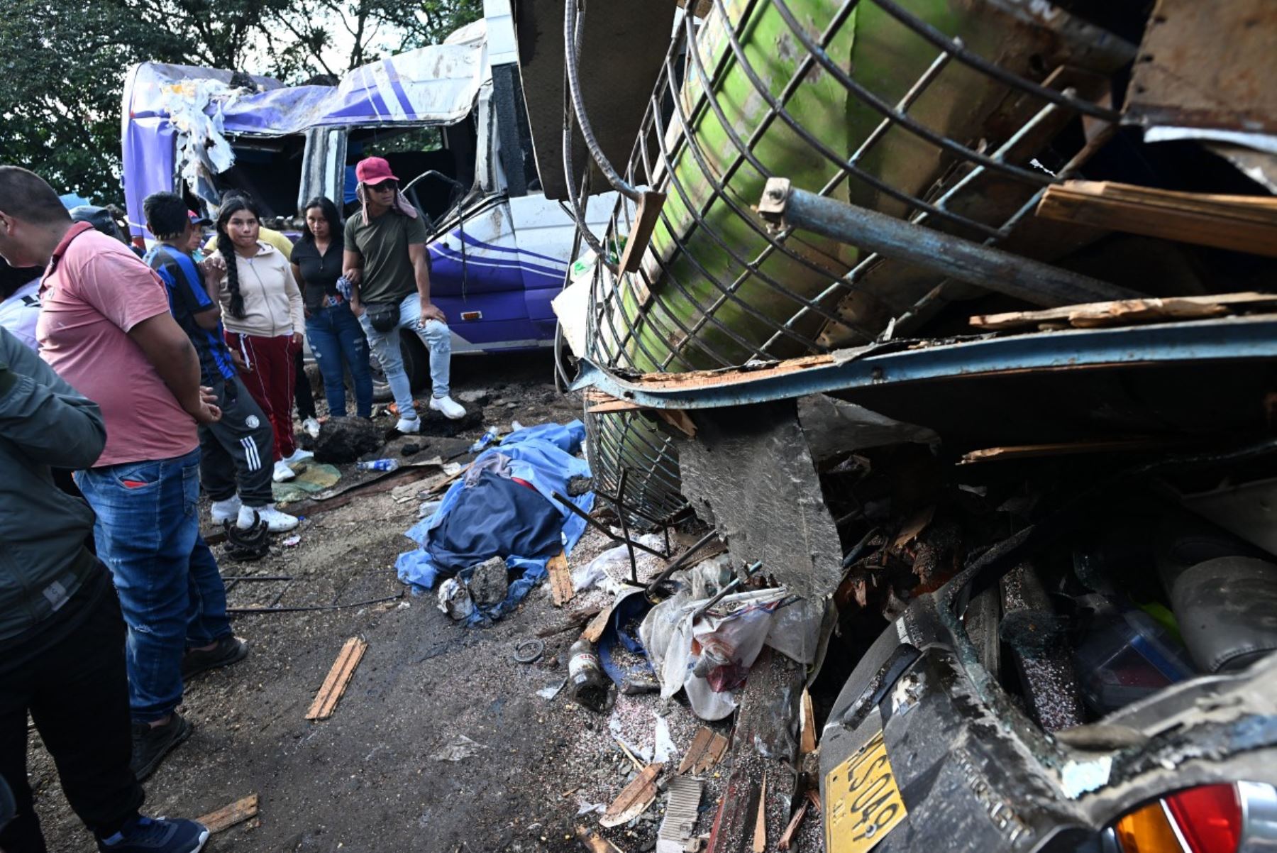 Varias personas se encuentran junto al cuerpo de una de las víctimas, cubierto con una sábana azul, tras un atentado con bomba en El Túnel, en la carretera Popayán-Cali, en Cajibio, departamento del Cauca, Colombia, el 25 de abril de 2026. Foto: AFP