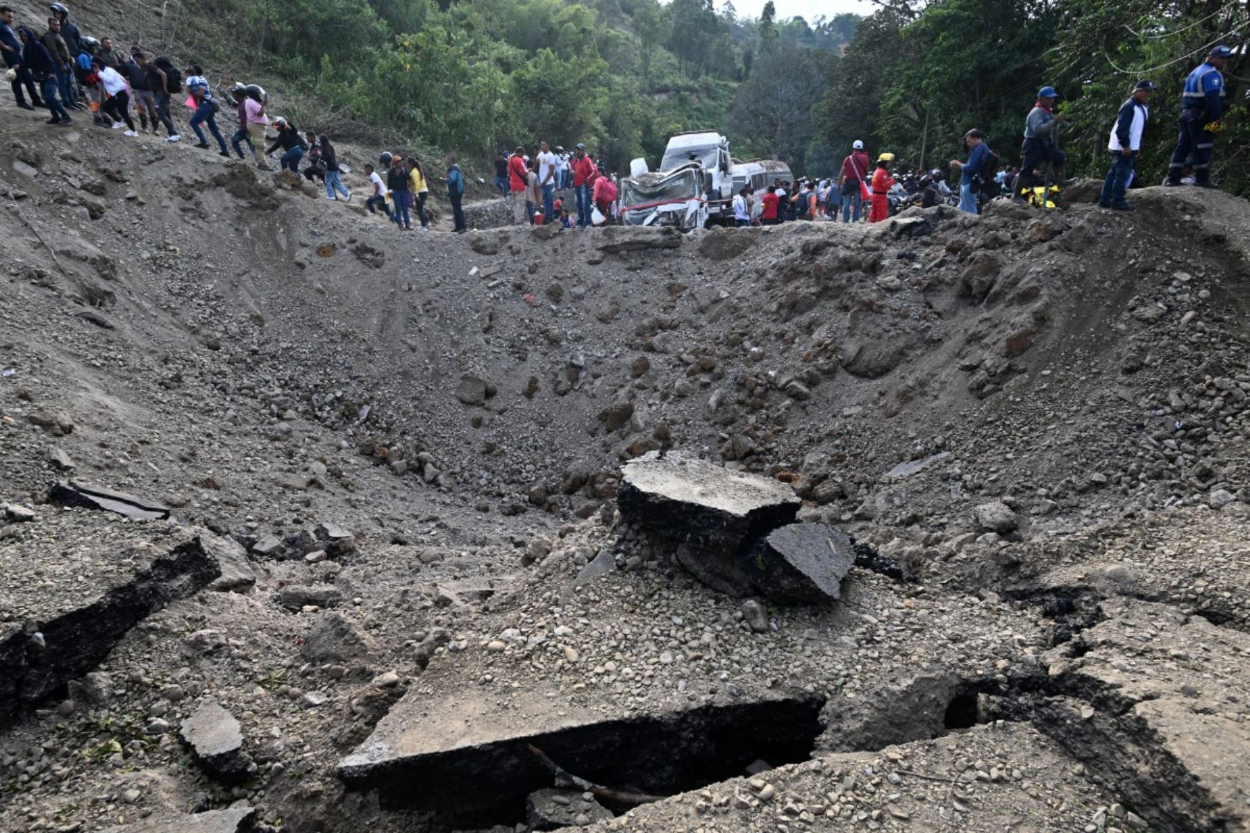 Varias personas pasan junto al lugar de una explosión tras un atentado con bomba en El Túnel, en la carretera Popayán-Cali, en Cajibio, departamento del Cauca, Colombia, el 25 de abril de 2026. Foto: AFP