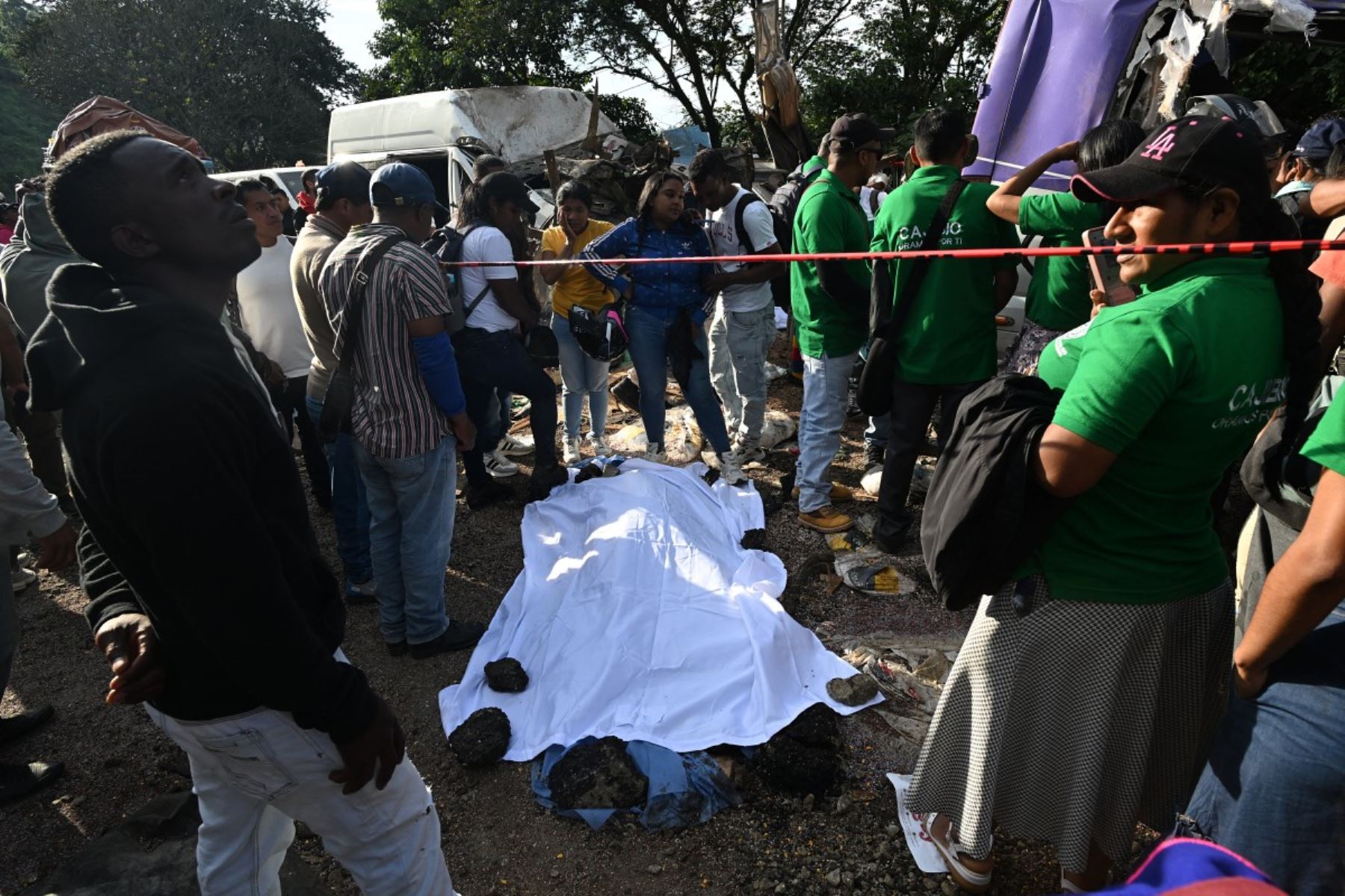 Varias personas rodean el cuerpo de una de las víctimas, cubierto con una sábana blanca, tras un atentado con bomba en El Túnel, en la carretera Popayán-Cali, en Cajibio, departamento del Cauca, Colombia, el 25 de abril de 2026. Foto: AFP