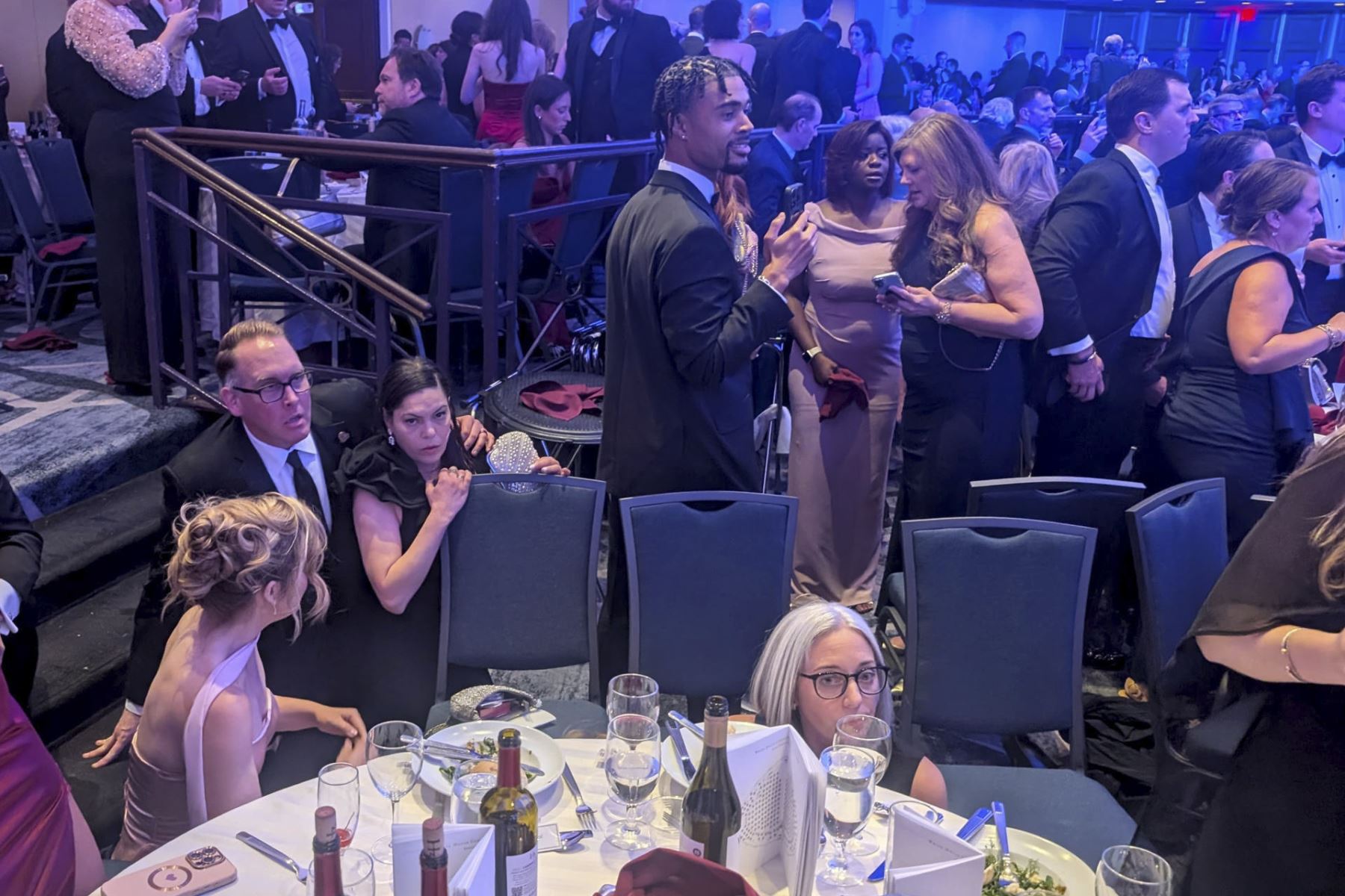 Personas reaccionan tras escuchar aparentes disparos durante la cena anual de la Asociación de Corresponsales de la Casa Blanca (WHCA) este sábado, en Washigton (Estados Unidos). EFE/ Eduard Ribas
