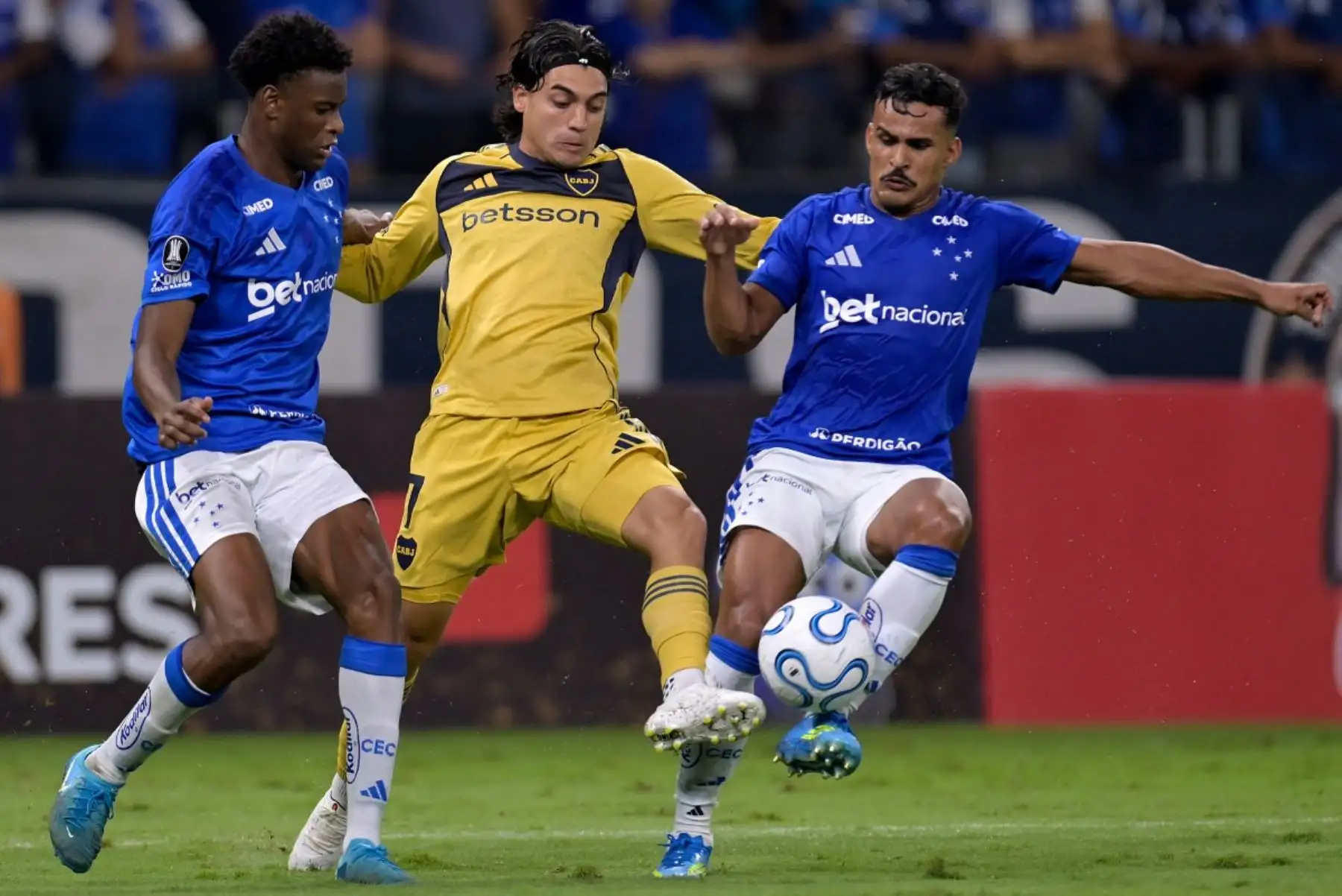 El delantero de Boca Juniors #07 Exequiel Zeballos (C) lucha por el balón con el defensor de Cruzeiro #34 Jonathan Jesus (L) y el defensor #06 Kaiki durante el partido de fútbol de la fase de grupos de la Copa Libertadores entre el Cruzeiro de Brasil y el Boca Juniors de Argentina en el estadio Mineirao en Belo Horizonte, estado de Minas Gerais, Brasil, el 28 de abril de 2026. (Foto de DOUGLAS MAGNO / AFP)