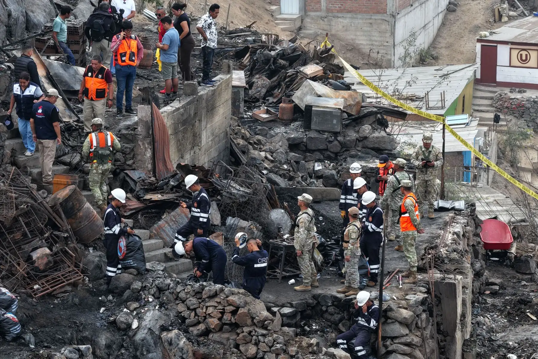 Efectivos de la Policía Nacional, del Ejército, y miembros de Defensa Civil y otras instituciones públicas ayudan en la limpieza y remoción de escombros en la zona afectada por el incendio ocurrido en un cerro del AA.HH. Pampa de Cueva en Independencia el 1 de mayo de 2026. Foto: ANDINA/Daniel Bracamonte