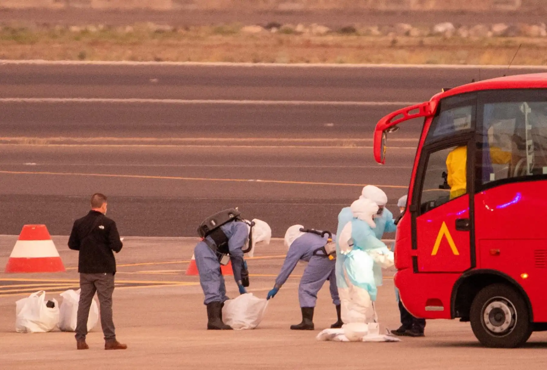 En la imagen se ve a personas con trajes de protección biológica mientras los pasajeros abordan un avión con destino a Estados Unidos que transporta a los pasajeros evacuados del crucero MV Hondius, de bandera holandesa y afectado por el hantavirus, en el aeropuerto de Tenerife Sur-Reina Sofía, en la isla de Tenerife, en las Islas Canarias, España, el 10 de mayo de 2026. Foto: AFP