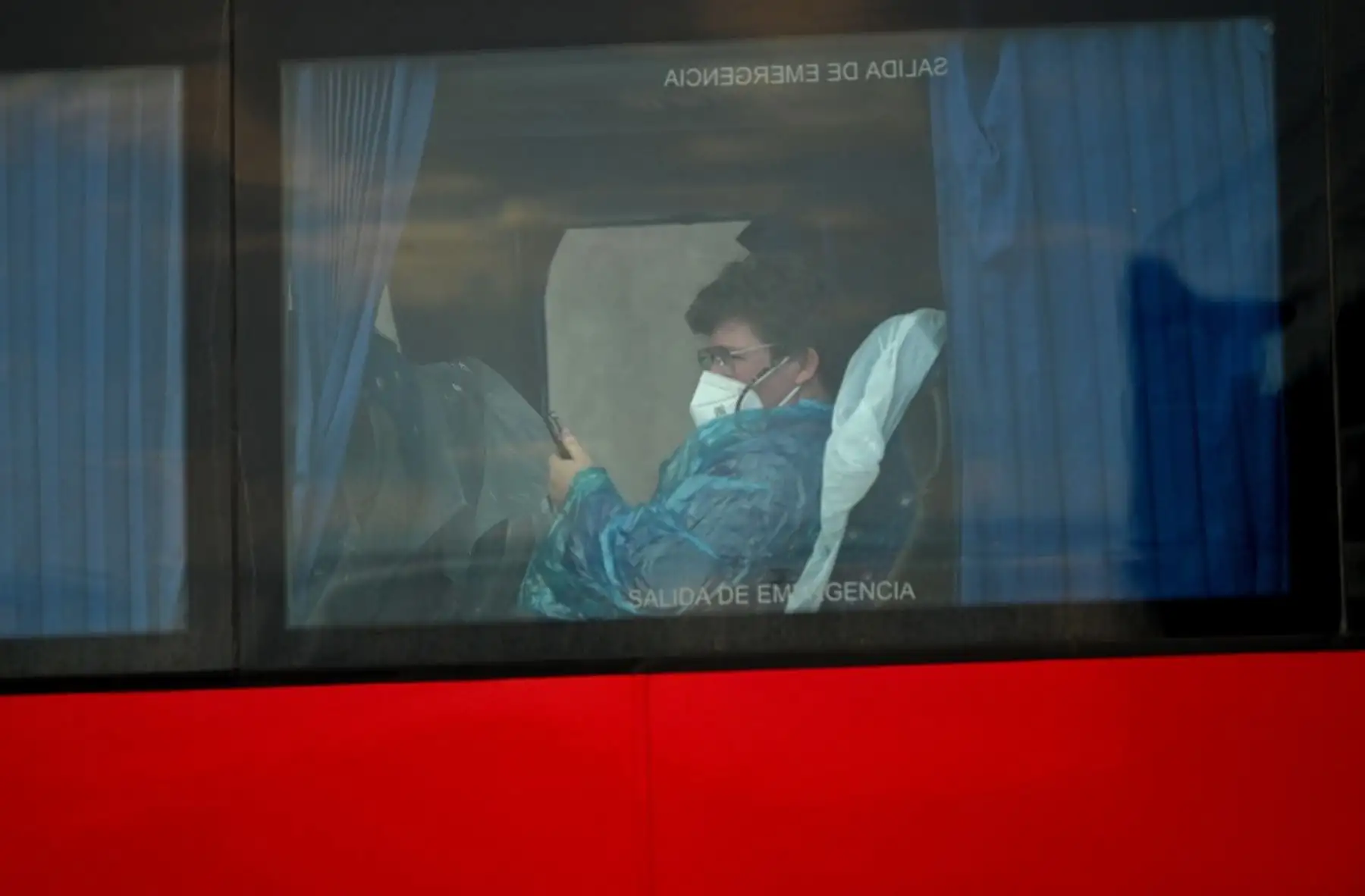 En la fotografía aparece un pasajero estadounidense evacuado del crucero MV Hondius, con bandera holandesa y afectado por el hantavirus, a bordo de un autobús militar tras ser trasladado en barco al puerto industrial de Granadilla de Abona, en la isla de Tenerife, en las Islas Canarias de España, el 10 de mayo de 2026. Foto: AFP
