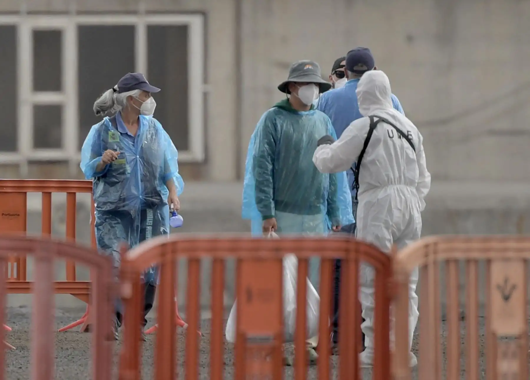 Pasajeros turcos del crucero MV Hondius, con bandera holandesa y afectado por el hantavirus, conversan con personal con trajes de protección contra materiales peligrosos mientras desembarcan en el puerto industrial de Granadilla de Abona, en la isla de Tenerife, en las Islas Canarias de España, el 10 de mayo de 2026. Foto: AFP
