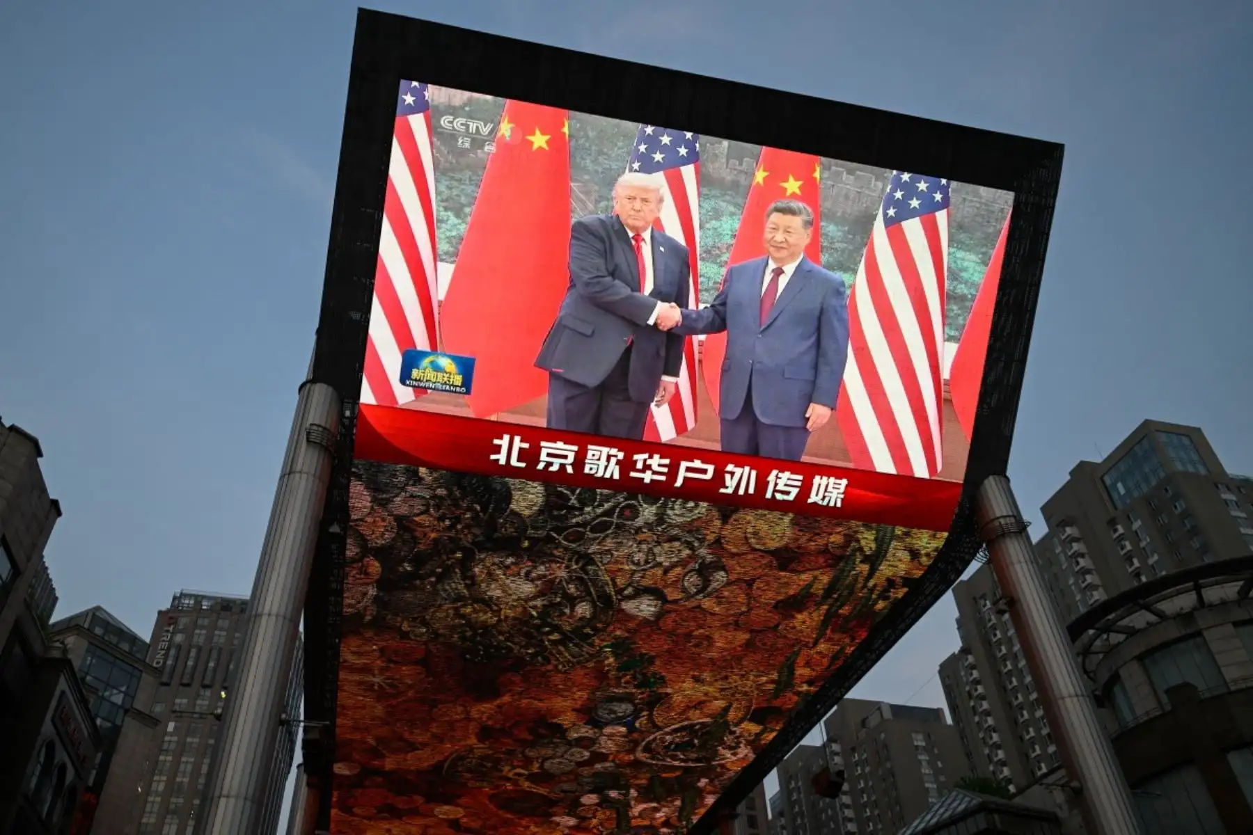Una gran pantalla muestra la retransmisión del encuentro entre el presidente chino Xi Jinping y el presidente estadounidense Donald Trump en el Gran Salón del Pueblo en Pekín. Foto: AFP