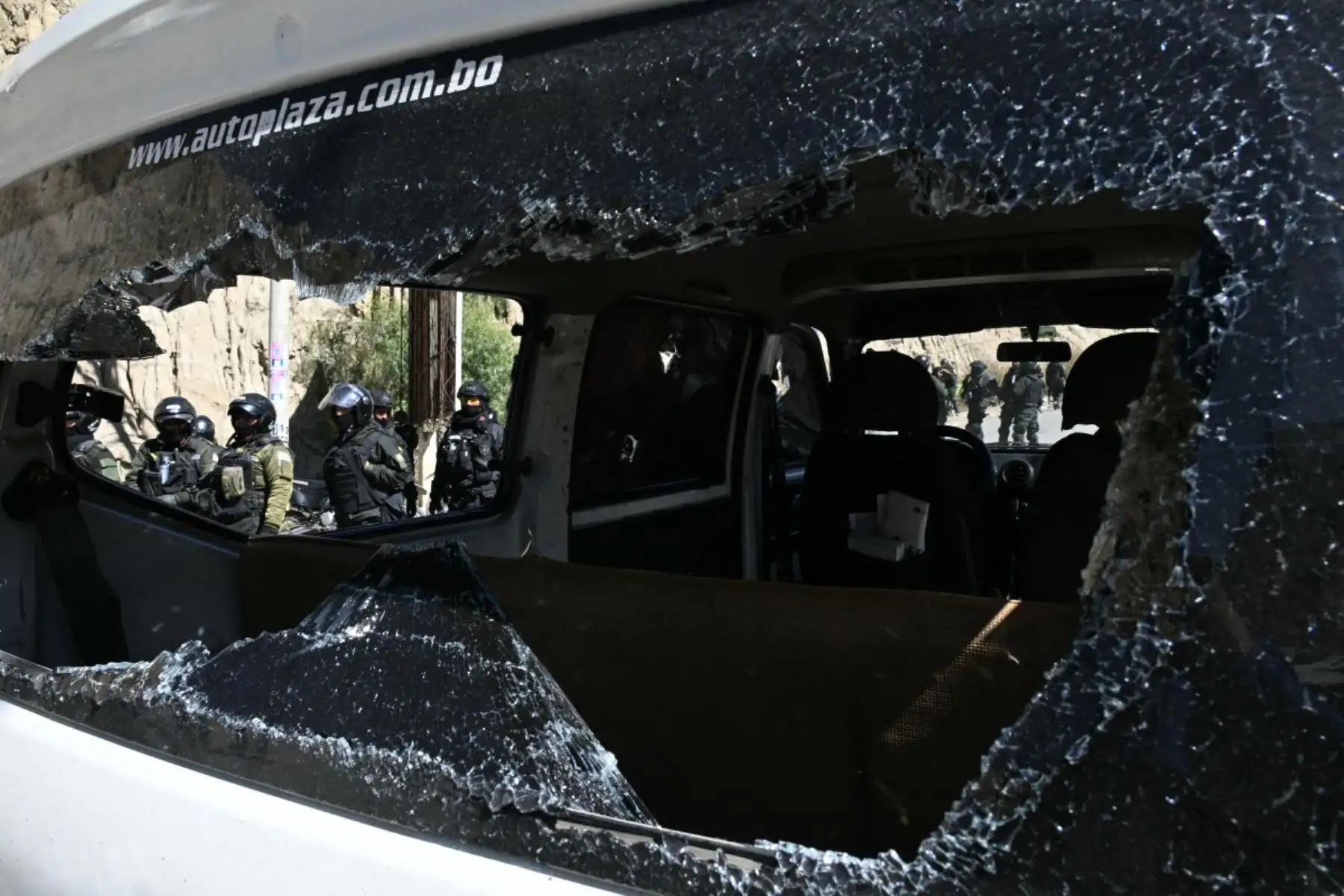 Los agentes de policía antidisturbios se paran junto a un vehículo con el parabrisas destrozado durante los enfrentamientos con manifestantes rurales en Lipari, departamento de La Paz, Bolivia, el 16 de mayo de 2026. El gobierno de Bolivia llegó a un acuerdo el 15 de mayo con miles de mineros que se enfrentaron a la policía en una protesta que paralizó el centro de La Paz. Sin embargo, otros sectores continúan bloqueando las rutas de acceso a la ciudad, hogar del poder ejecutivo y el Congreso. (Foto de AIZA