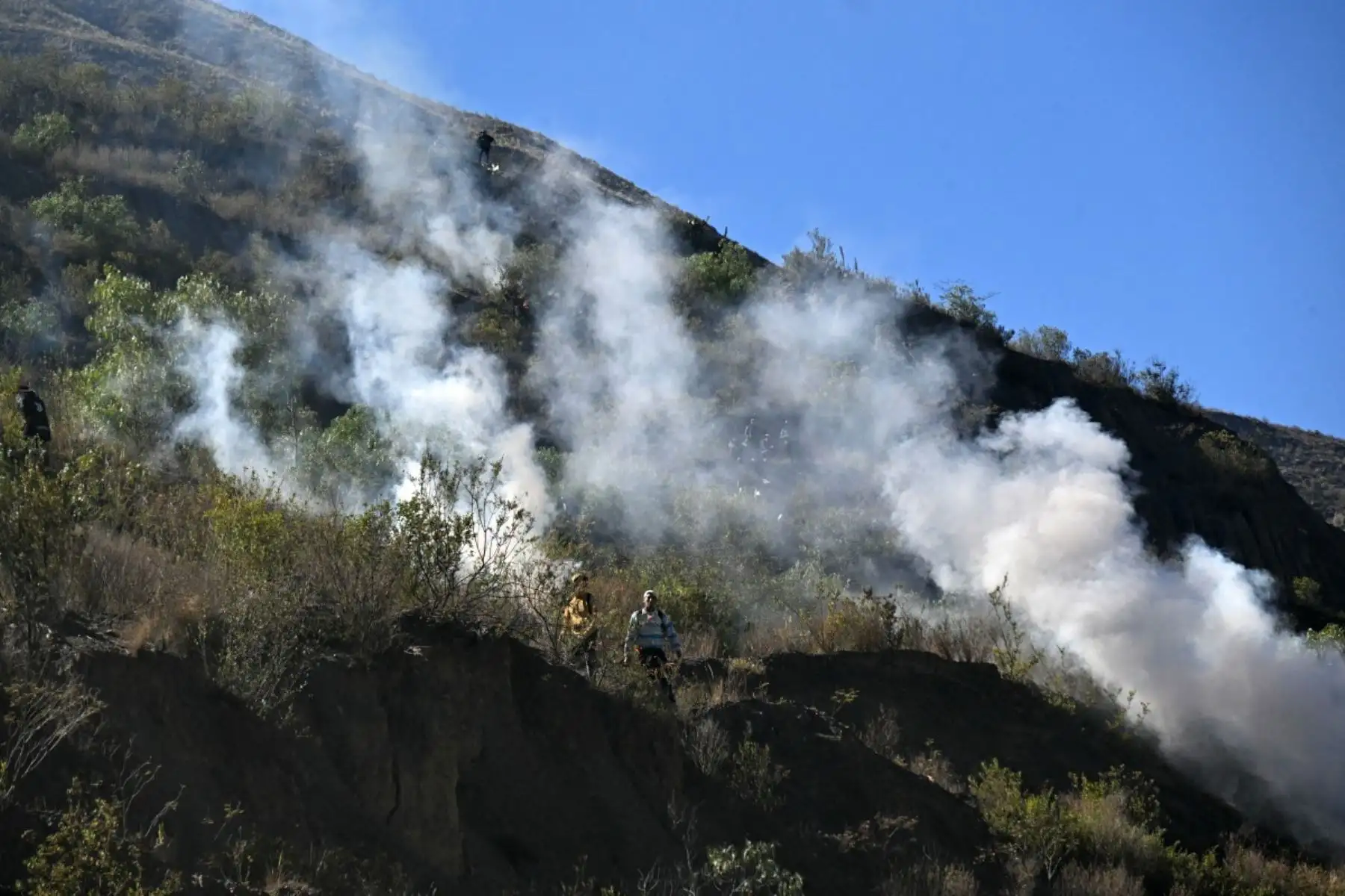 Los manifestantes rurales se mueven a través de gases lacrimógenos en una ladera durante los enfrentamientos con la policía antidisturbios en Lipari, departamento de La Paz, Bolivia, el 16 de mayo de 2026. El gobierno de Bolivia llegó a un acuerdo el 15 de mayo con miles de mineros que se enfrentaron a la policía en una protesta que paralizó el centro de La Paz. Sin embargo, otros sectores continúan bloqueando las rutas de acceso a la ciudad, hogar del poder ejecutivo y el Congreso. (Foto de AIZAR RALDES /