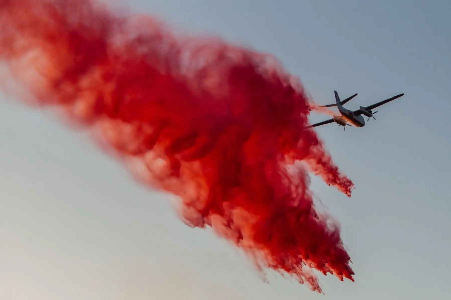 Un avión de Cal Fire arroja retardante de fuego sobre el incendio Sandy, que arde en las colinas cercanas a una zona residencial en Simi Valley, California. Foto: AFP