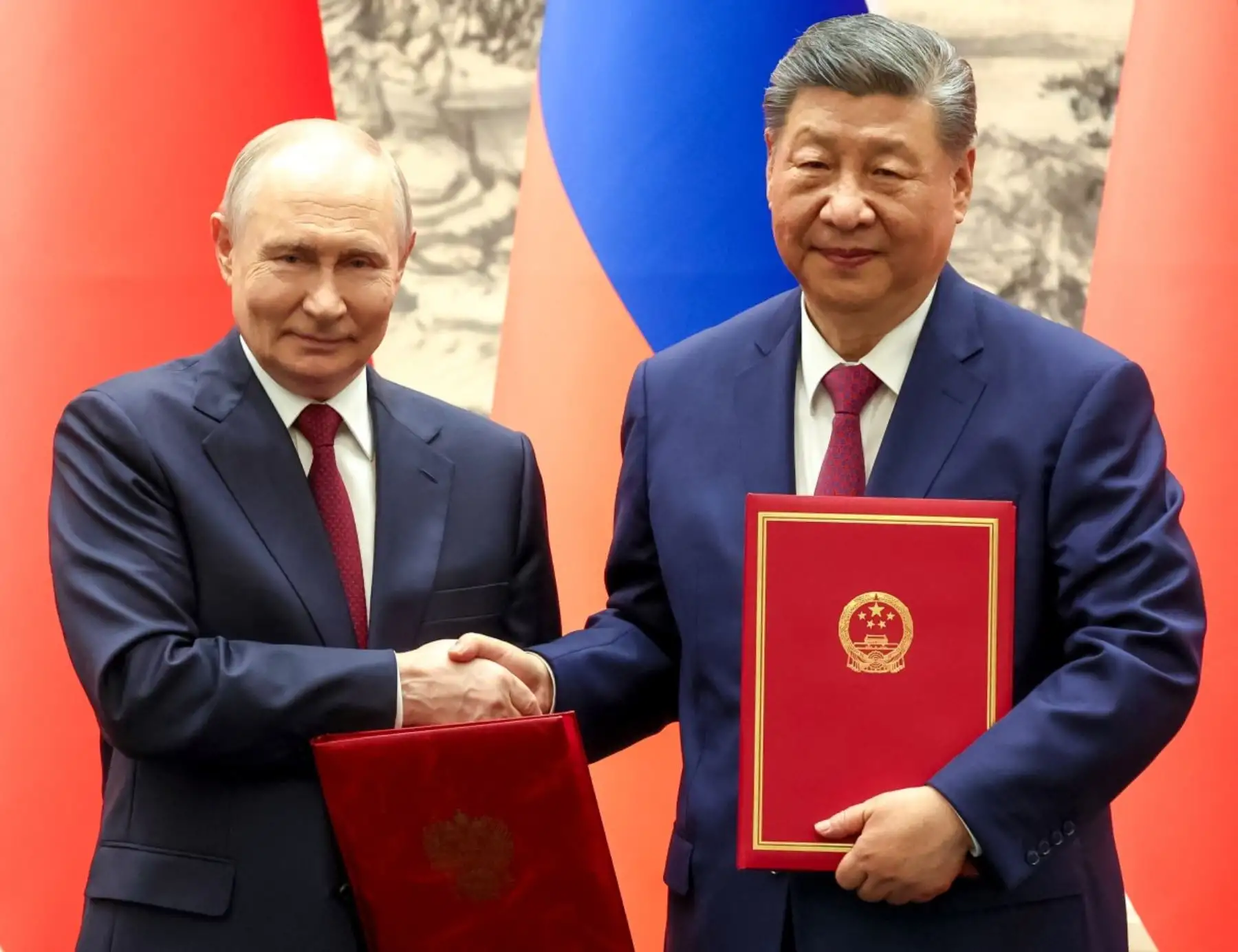 El presidente ruso Vladimir Putin y el presidente chino Xi Jinping se dan la mano durante una ceremonia de firma tras sus conversaciones en Pekín. Foto: AFP