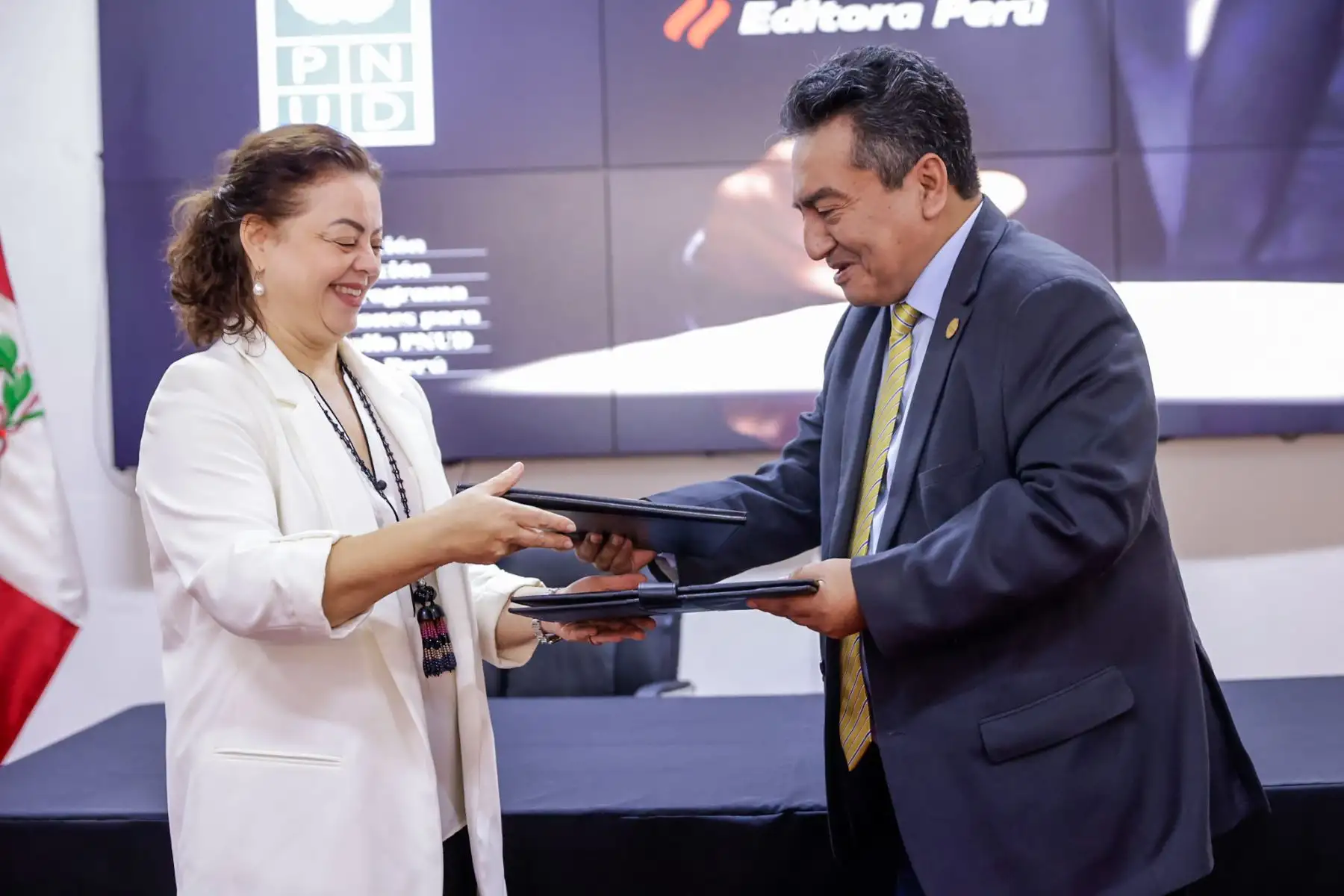 La representante residente del PNUD en el Perú, Alissar Chaker, y el gerente general de Editora Perú, Félix Paz Quiroz, intercambiaron el documento suscrito durante la ceremonia protocolar. Foto: ANDINA/Luis Iparraguirre.