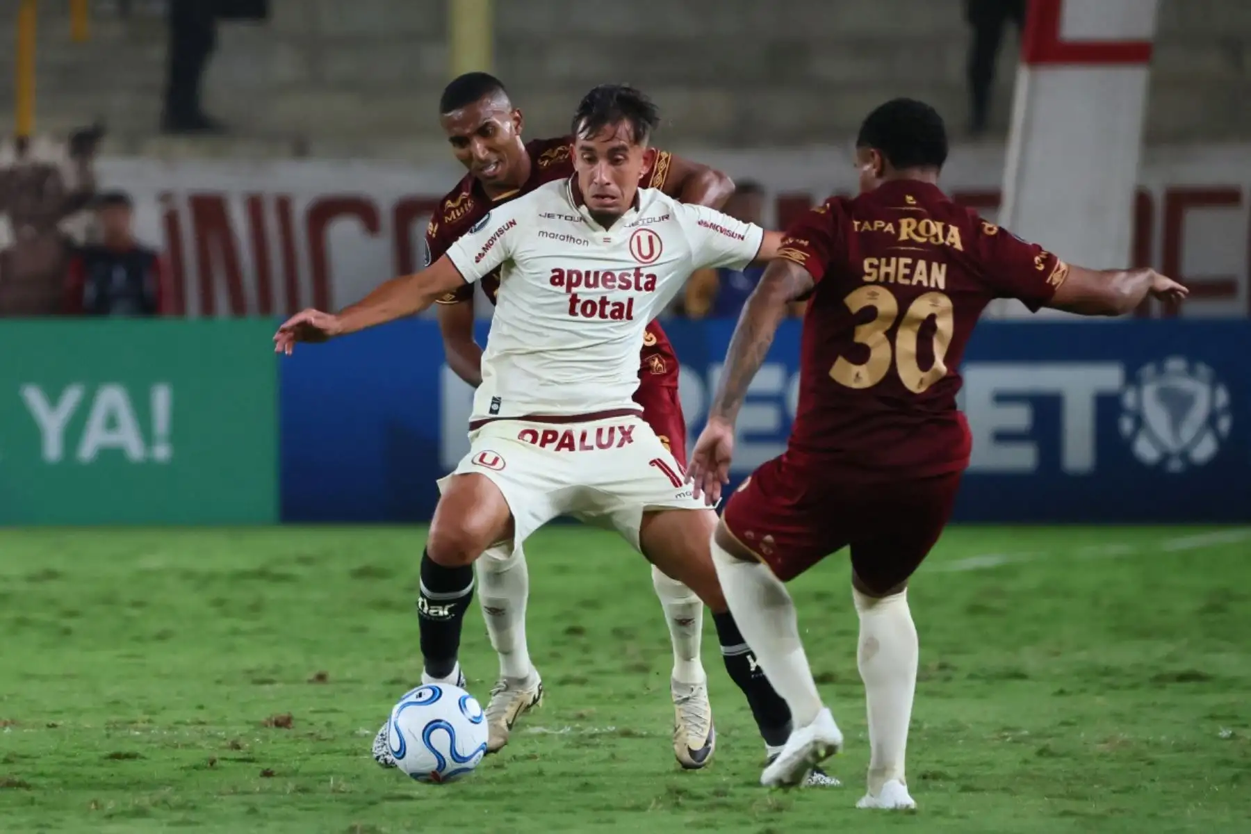 El mediocampista argentino del Universitario, Martín Pérez (C), número 16, disputa el balón con el mediocampista del Tolima, Cristian Trujillo (atrás), número 6, y el defensor Shean Barbosa, número 30, durante el partido de la fase de grupos de la Copa Libertadores entre el Universitario de Perú y el Deportes Tolima de Colombia en el Estadio Monumental "U" Marathon de Lima, el 26 de mayo de 2026. (Foto de Connie FRANCE / AFP)