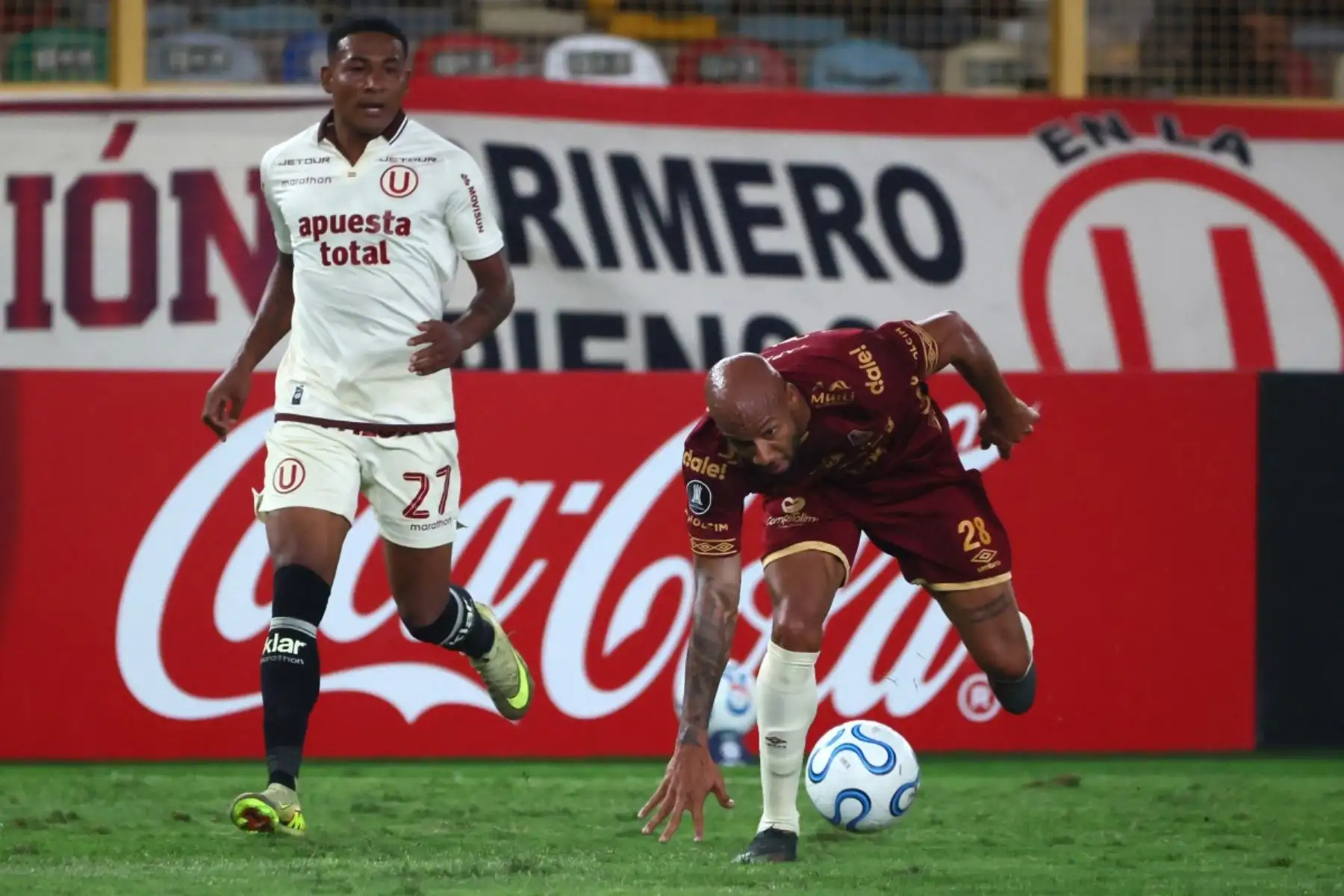 El centrocampista ecuatoriano del Universitario, José Carabali (número 27), y el delantero del Tolima, Edwar López (número 28), corren por el balón durante el partido de la fase de grupos de la Copa Libertadores entre el Universitario de Perú y el Deportes Tolima de Colombia en el Estadio Monumental "U" Marathon de Lima, el 26 de mayo de 2026. (Foto de Connie FRANCE / AFP)