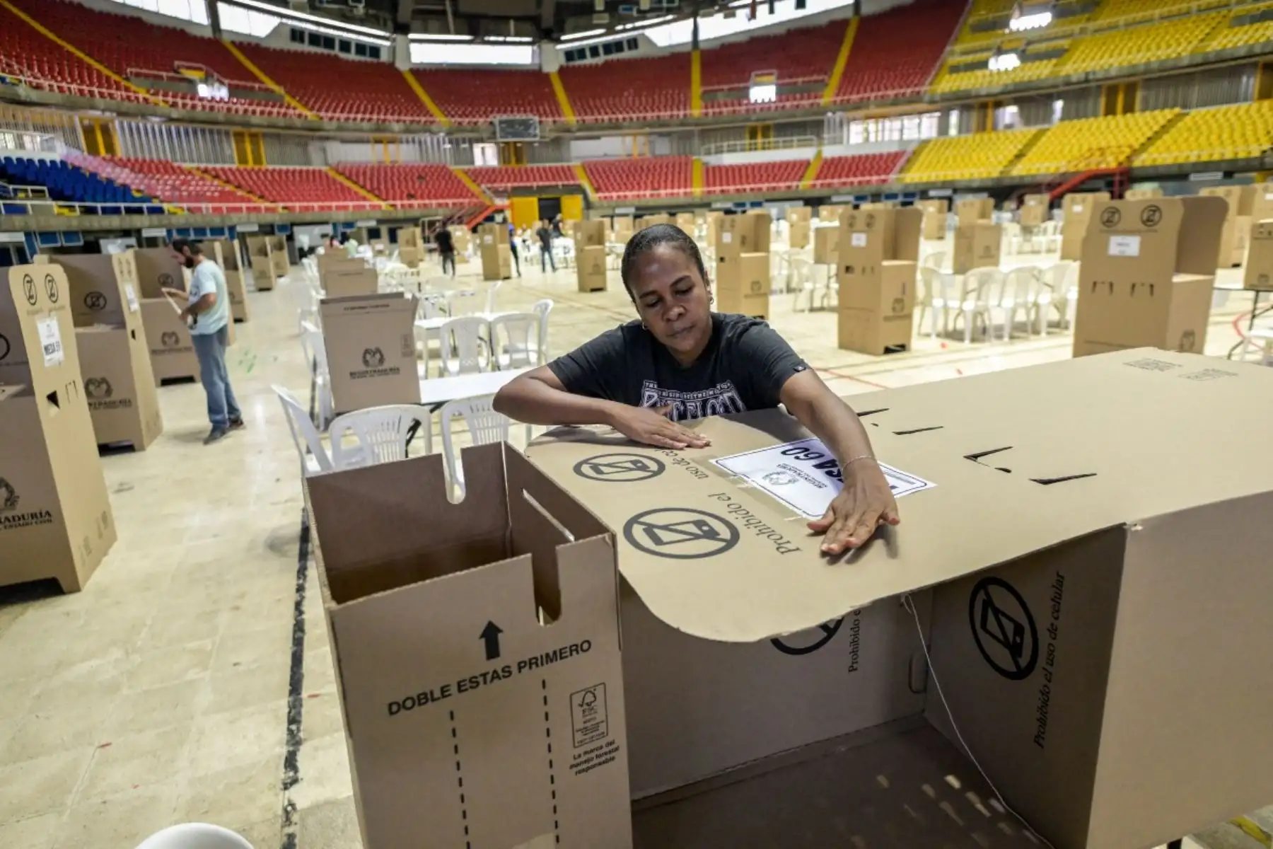 Un trabajador ensambla una cabina de votación durante los preparativos en el Coliseo El Pueblo en Cali, departamento del Valle del Cauca, Colombia, el 30 de mayo de 2026, víspera de las elecciones presidenciales. Foto: AFP