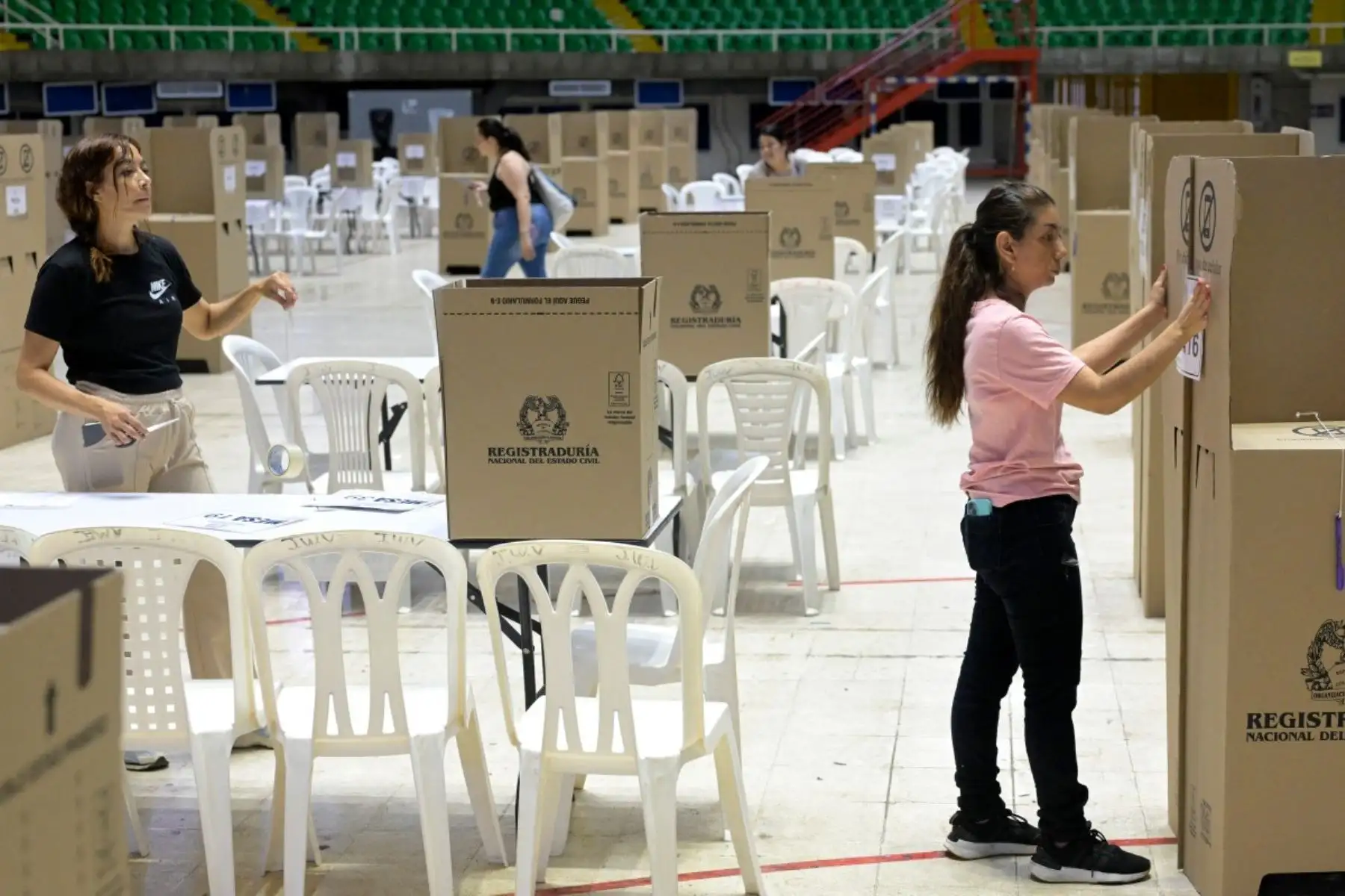 Un trabajador ensambla una cabina de votación durante los preparativos en el Coliseo El Pueblo en Cali, departamento del Valle del Cauca, Colombia, el 30 de mayo de 2026, víspera de las elecciones presidenciales. Foto: AFP