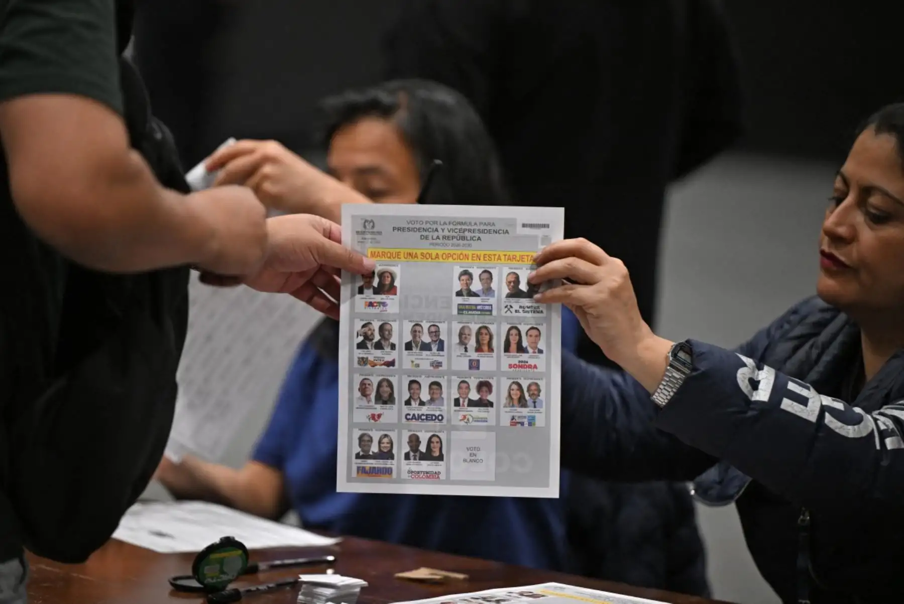 Miembros de mesa entregan las cédulas electorales a los ciudadanos que participan en la jornada democrática para elegir al próximo presidente de Colombia. Fotos: AFP.