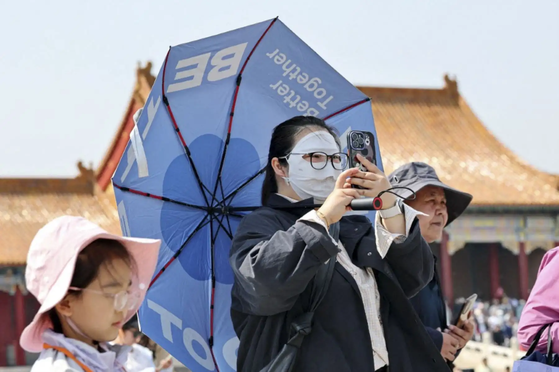 Los turistas usan paraguas, ropa de protección solar, sombreros y gafas de sol para protegerse de la luz solar intensa en la Ciudad Prohibida en Beijing, capital de China. (Foto de Shun Qiziran / foto IC / Imaginechina vía AFP)