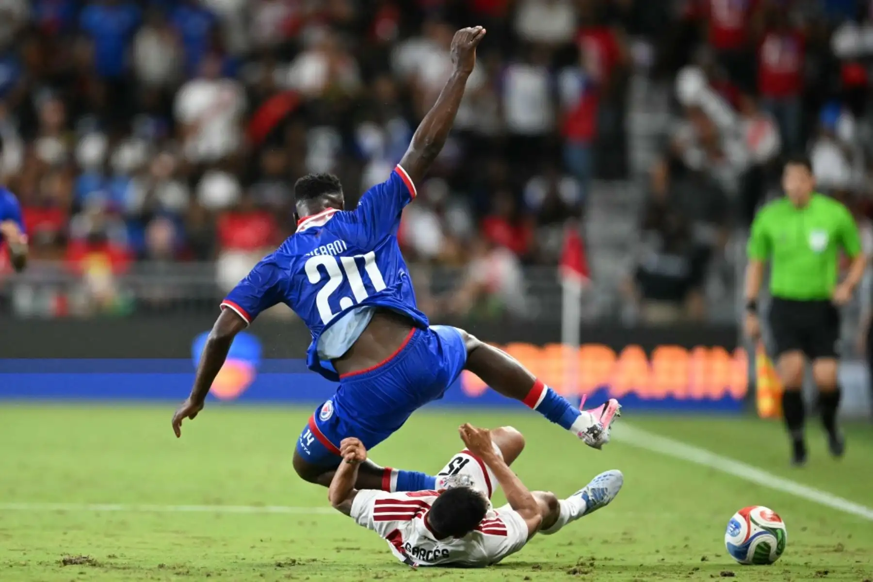 El delantero haitiano Frantzdy Pierrot (número 20) y el defensa peruano Renzo Garces (número 15) caen al suelo mientras disputan el balón durante el partido amistoso internacional de fútbol entre Haití y Perú en el Estadio Nu de Miami, Florida, el 5 de junio de 2026. (Foto de CHANDAN KHANNA / AFP)