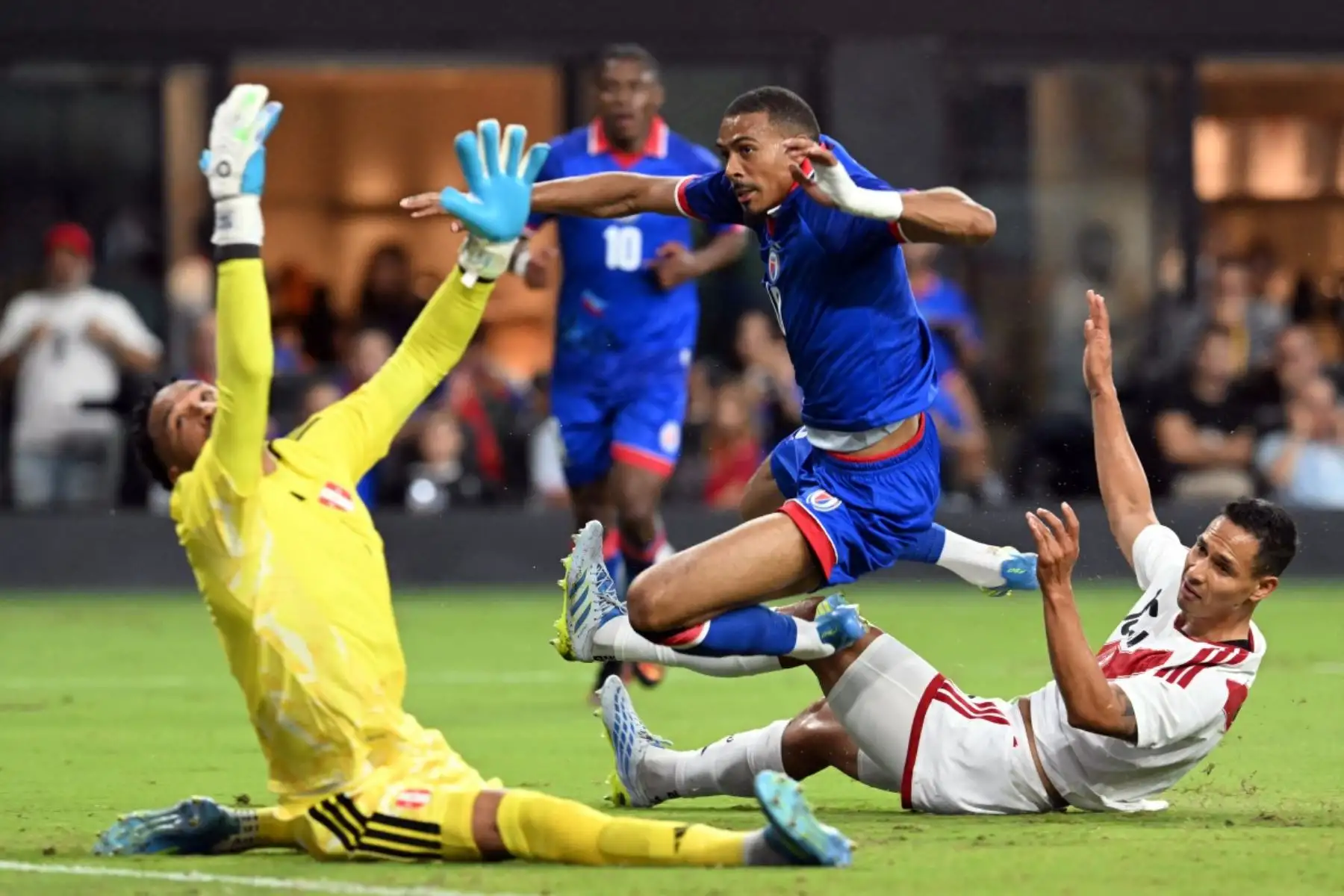 El delantero haitiano Wilson Isidor (C), número 18, salta por encima de un defensor peruano para batir al portero peruano Pedro Gallese (I), número 1, y marcar un gol durante el partido amistoso internacional de fútbol entre Haití y Perú en el Estadio Nu de Miami, Florida, el 5 de junio de 2026. (Foto de CHANDAN KHANNA / AFP)