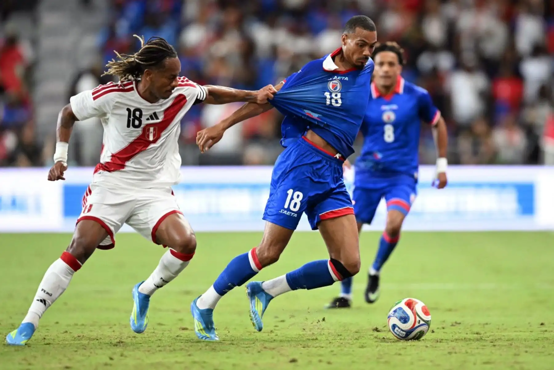 El delantero haitiano Wilson Isidor (derecha), número 18, y el delantero peruano André Carrillo, número 18, luchan por el balón durante el partido amistoso internacional de fútbol entre Haití y Perú en el Estadio Nu de Miami, Florida, el 5 de junio de 2026. (Foto de CHANDAN KHANNA / AFP)