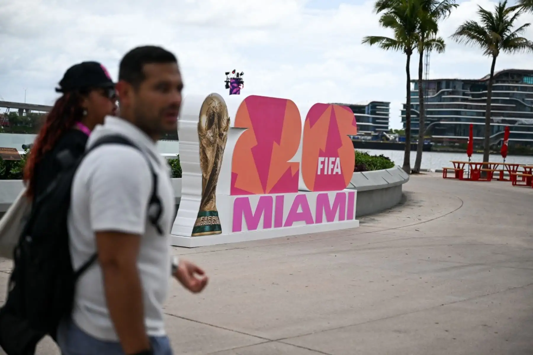 Los peatones pasan junto al logotipo del evento con el trofeo de la competición antes de la inauguración del FIFA Fan Festival Miami, previo al torneo de fútbol de la Copa Mundial de 2026 en Miami, Florida. AFP