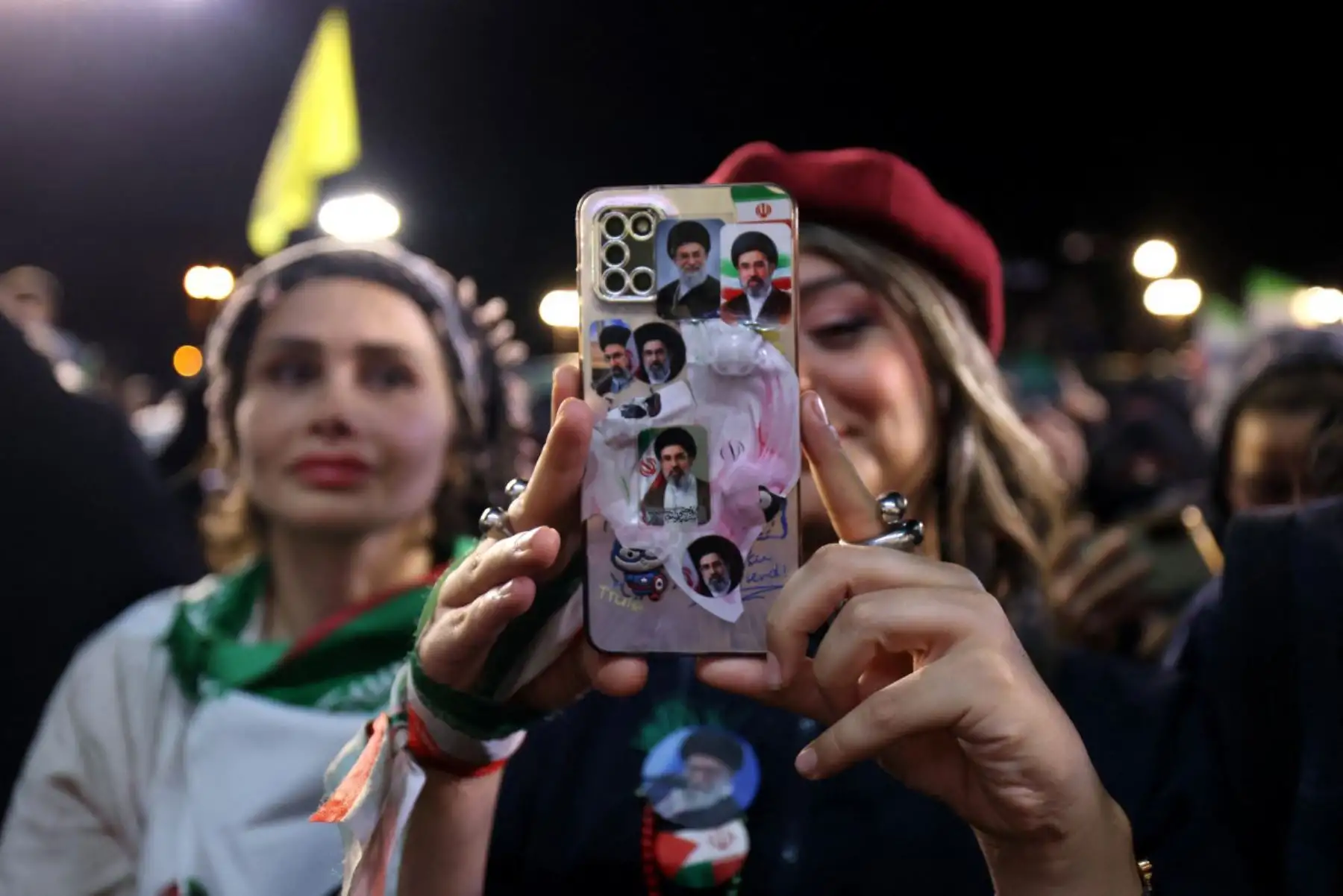 Una mujer, con su teléfono móvil que contiene fotos del actual líder supremo de Irán, el ayatolá Mojtaba Khamenei, toma fotografías de la ceremonia de despedida de la selección nacional de fútbol de Irán antes de su partida para la Copa Mundial de la FIFA 2026, en Teherán. Foto: AFP