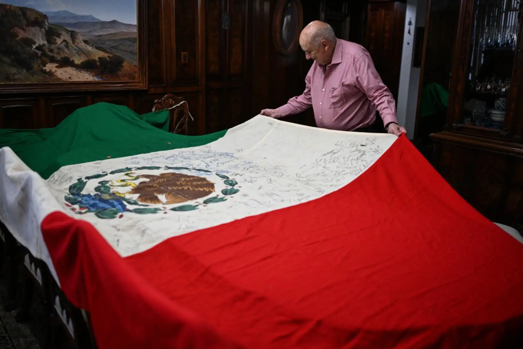 El mexicano Alberto Obregón exhibe una bandera nacional firmada por jugadores de la selección mexicana desde la primera Copa Mundial de la FIFA celebrada en México en 1970 —fecha desde la cual colecciona autógrafos— en su casa de Cuajimalpa, Ciudad de México. Obregón relata que la bandera le ha servido como punto de referencia para recopilar la historia de las Copas Mundiales celebradas en México. Foto: AFP