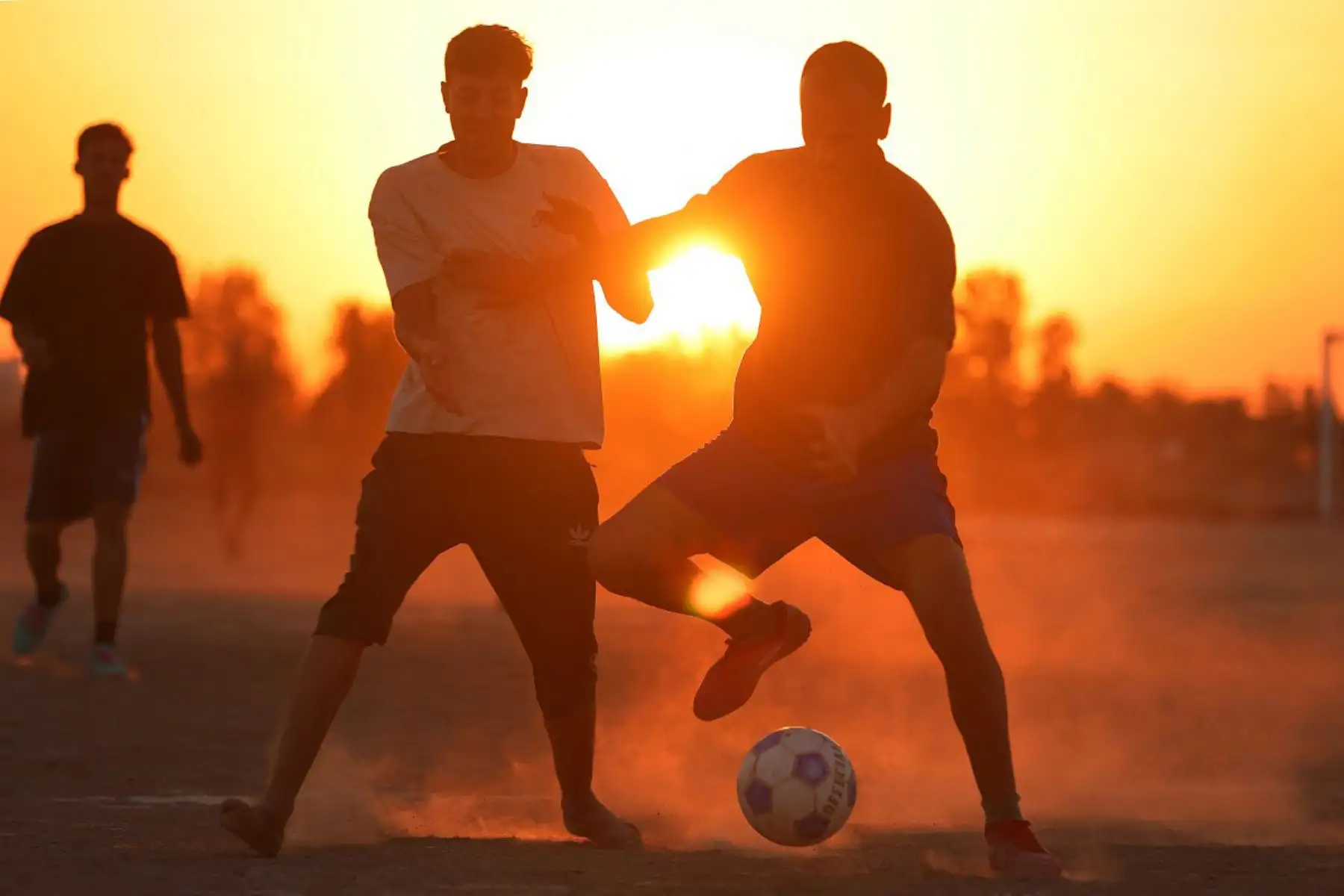 Iraquíes juegan al fútbol en un campo al atardecer en el distrito de Al-Qasim, en Hilla, al sur de Bagdad. Irak, cuyos preparativos se vieron interrumpidos por la guerra en Oriente Medio, selló su primera participación en la Copa Mundial de la FIFA 2026 en 40 años y jugará en el Grupo I contra Francia, Senegal y Noruega. Foto: AFP
