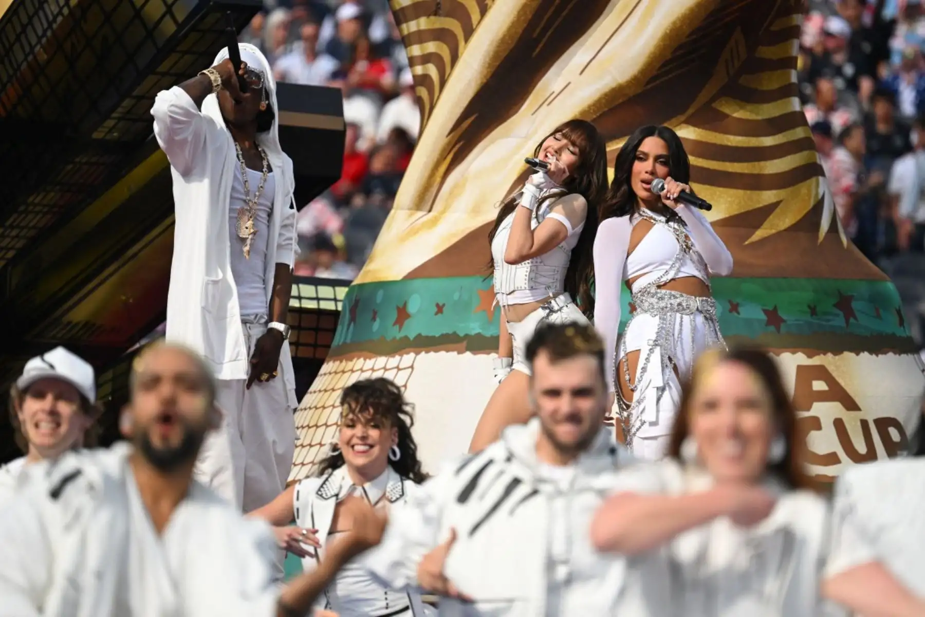 El rapero nigeriano Rema (izquierda), la rapera tailandesa Lisa (centro) y la cantautora brasileña Anitta (derecha) actúan durante la ceremonia de apertura del Mundial de Fútbol de 2026, antes del partido del Grupo D entre Estados Unidos y Paraguay en el Estadio de Los Ángeles en Inglewood, el 12 de junio de 2026. (Foto de Patrick T. Fallon / AFP)