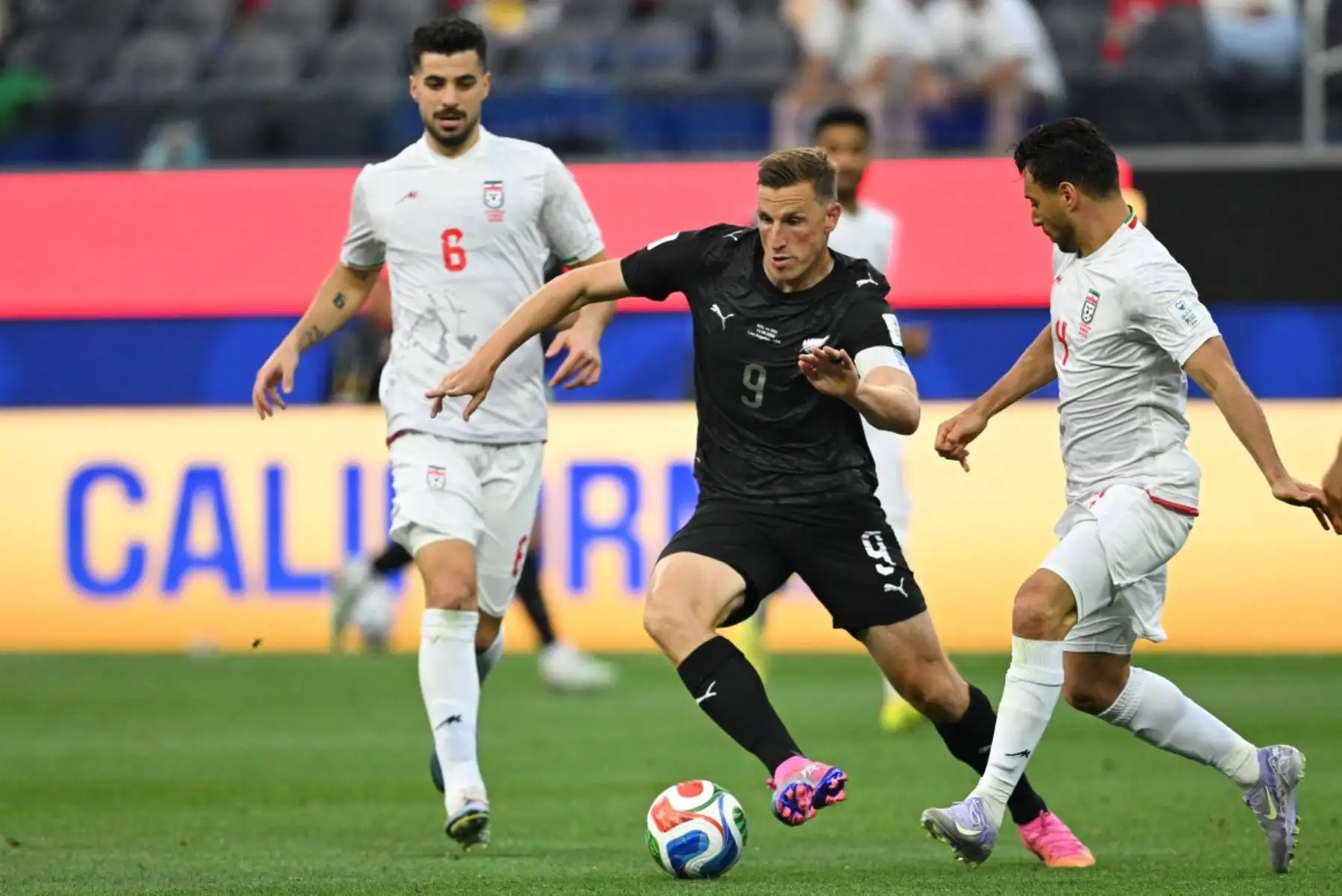 El delantero neozelandés Chris Wood, , corre con el balón superando al defensor iraní Shojae Khalilzadeh, , durante el partido de fútbol del Grupo G de la Copa Mundial 2026 entre Irán y Nueva Zelanda. AFP