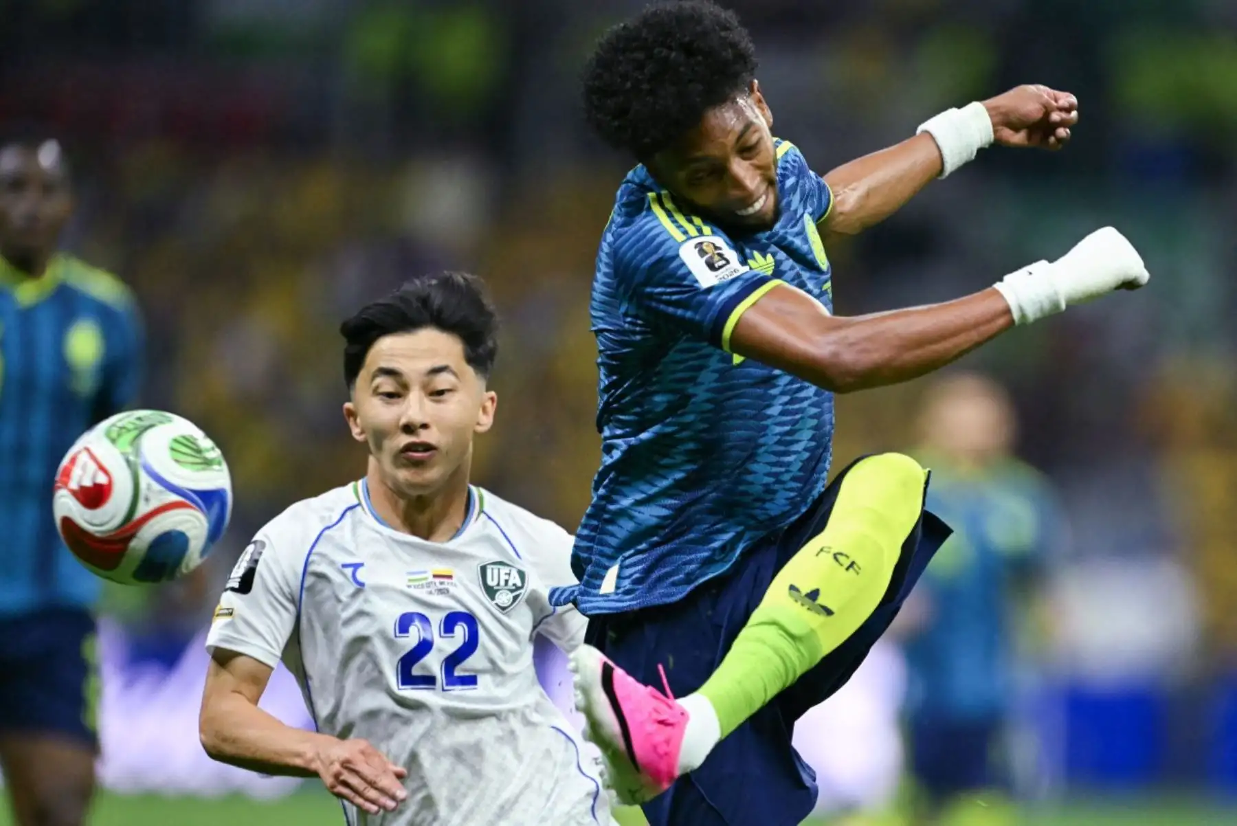 El defensa colombiano Johan Mojica  patea el balón superando al centrocampista uzbeko Abbosbek Fayzullaev, durante el partido de fútbol del Grupo K de la Copa Mundial 2026 entre Uzbekistán y Colombia. Foto: AFP