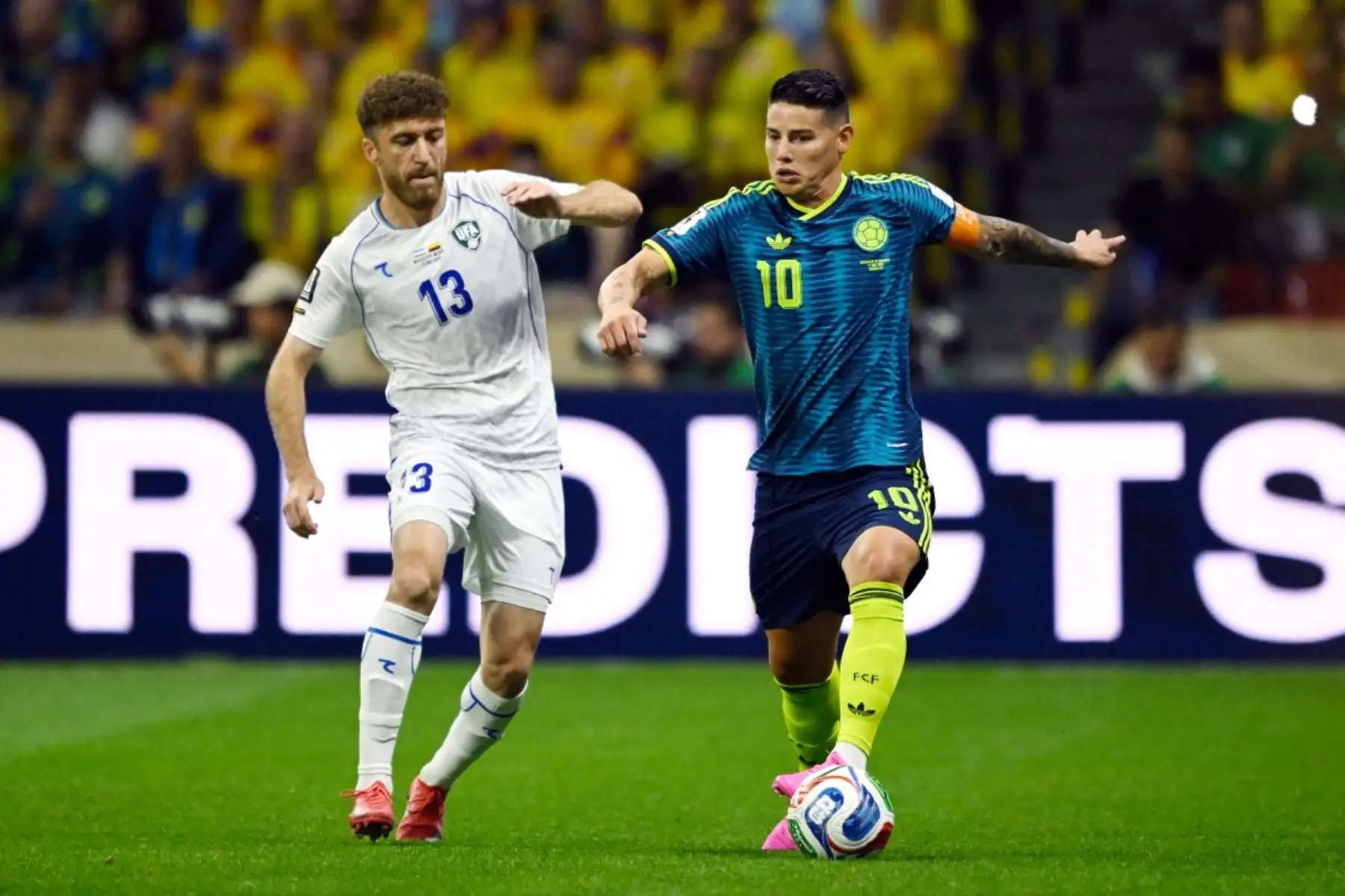 El centrocampista colombiano James Rodríguez  del ranking, avanza con el balón superando al defensor uzbeko Sherzod Nasrullaev  del ranking, durante el partido de fútbol del Grupo K de la Copa Mundial 2026 entre Uzbekistán y Colombia. AFP