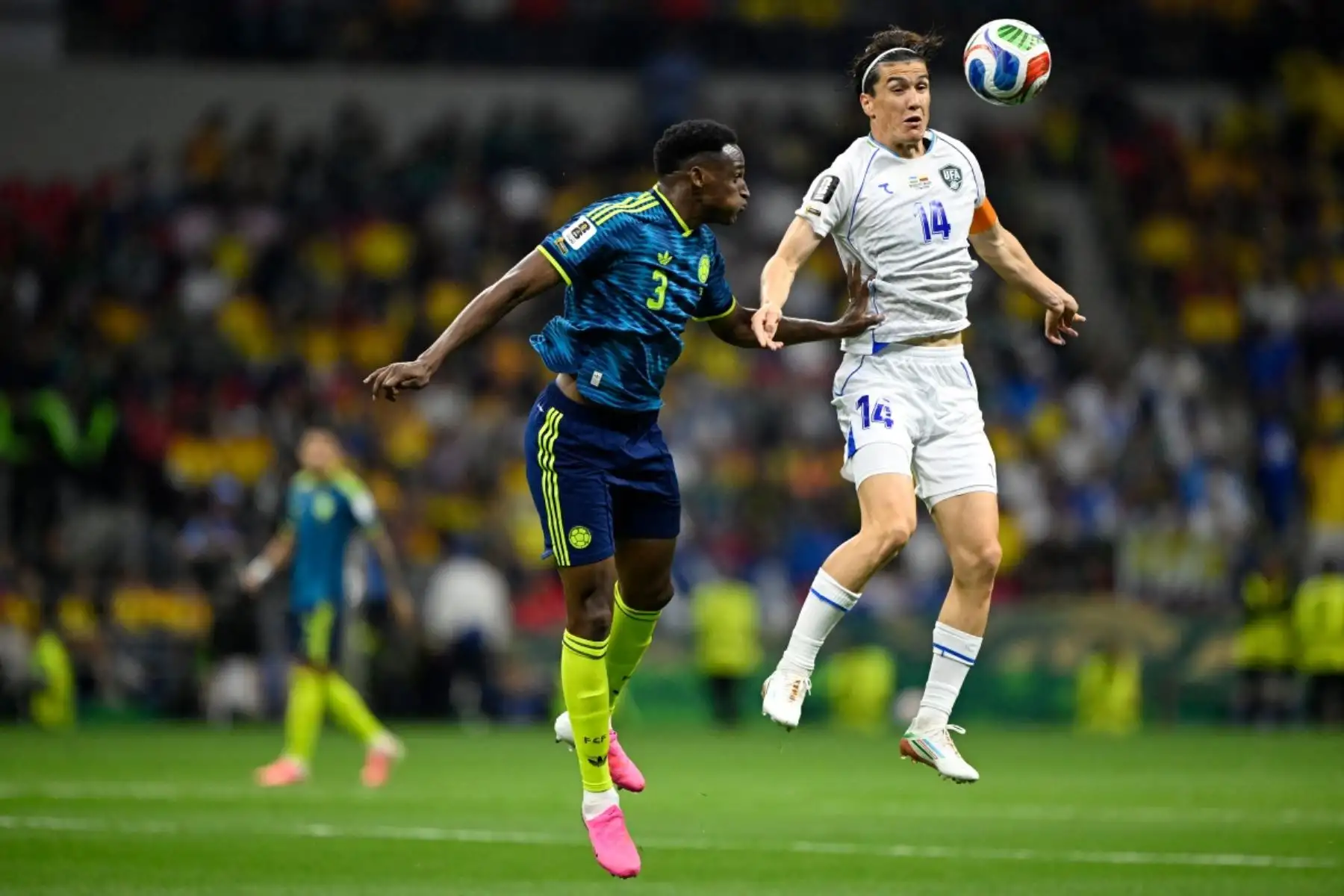 El defensa colombianoJhon Lucumí, y el delantero uzbeko  Eldor Shomurodov, luchan por el balón durante el partido de fútbol del Grupo K de la Copa Mundial 2026 entre Uzbekistán y Colombia. AFP