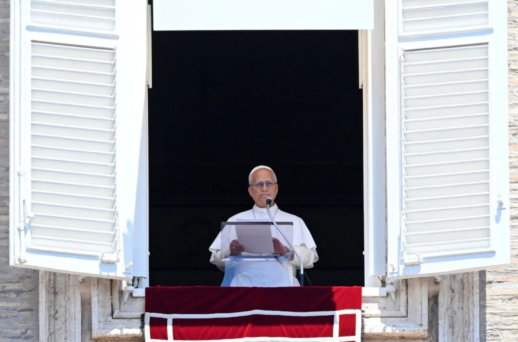 El papa León XIV se dirige a la multitud desde una ventana del palacio apostólico con vistas a la Plaza de San Pedro durante el rezo del Ángelus en el Vaticano. 
Foto: ANDINA/AFP