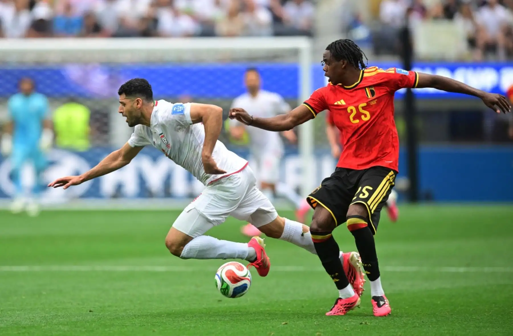 El delantero iraní Mehdi Taremi (n.º 09) y el defensa belga Nathan Ngoy (n.º 25) luchan por el balón durante el partido de fútbol del Grupo G de la Copa Mundial 2026 entre Bélgica e Irán en el Estadio de Los Ángeles en Inglewood el 21 de junio de 2026. (Foto de Frederic J. Brown / AFP)