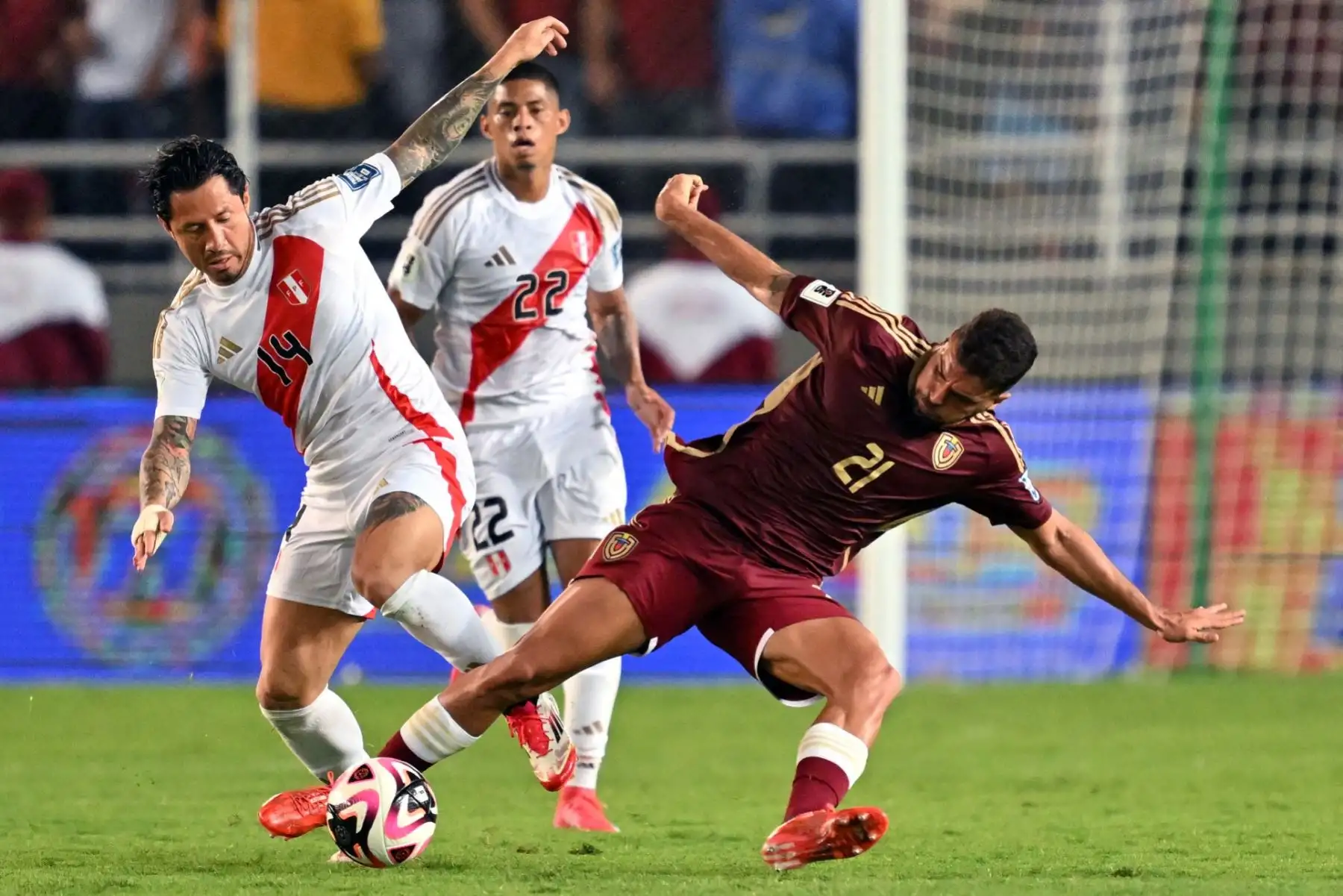 El delantero peruano #14 Gianluca Lapadula y el defensor #21 de Venezuela Alexander González luchan por el balón durante el partido de fútbol clasificatorio sudamericano de la Copa Mundial de la FIFA 2026 entre Venezuela y Perú en el estadio Monumental de Maturin en Maturin, estado de Monagas. Venezuela, el 25 de marzo de 2025. (Foto de JUAN BARRETO / AFP)