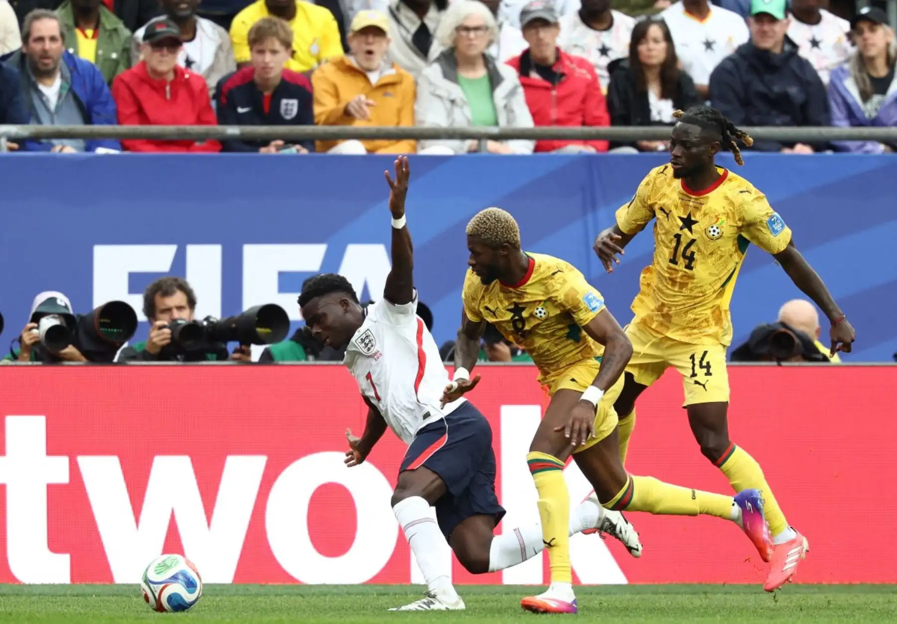 El delantero inglés Bukayo Saka (izq.), número 07, disputa el balón con el centrocampista ghanés Kwasi Sibo (centro), número 08, y el defensa ghanés Gideon Mensah (der.), número 14, durante el partido de fútbol del Grupo L de la Copa Mundial de 2026 entre Inglaterra y Ghana en el Boston Stadium de Foxborough el 23 de junio de 2026. (Foto de FRANCK FIFE / AFP)