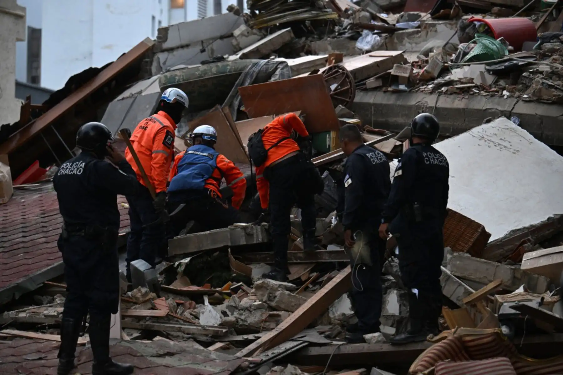 Los rescatistas buscan entre los restos de una estructura derrumbada mientras agentes de la policía municipal permanecen cerca tras el terremoto que sacudió Caracas. Un sismo de magnitud 7.1 sacudió Venezuela el miércoles, según informó el Servicio Geológico de Estados Unidos (USGS), provocando pánico en Caracas. Foto: ANDINA/AFP