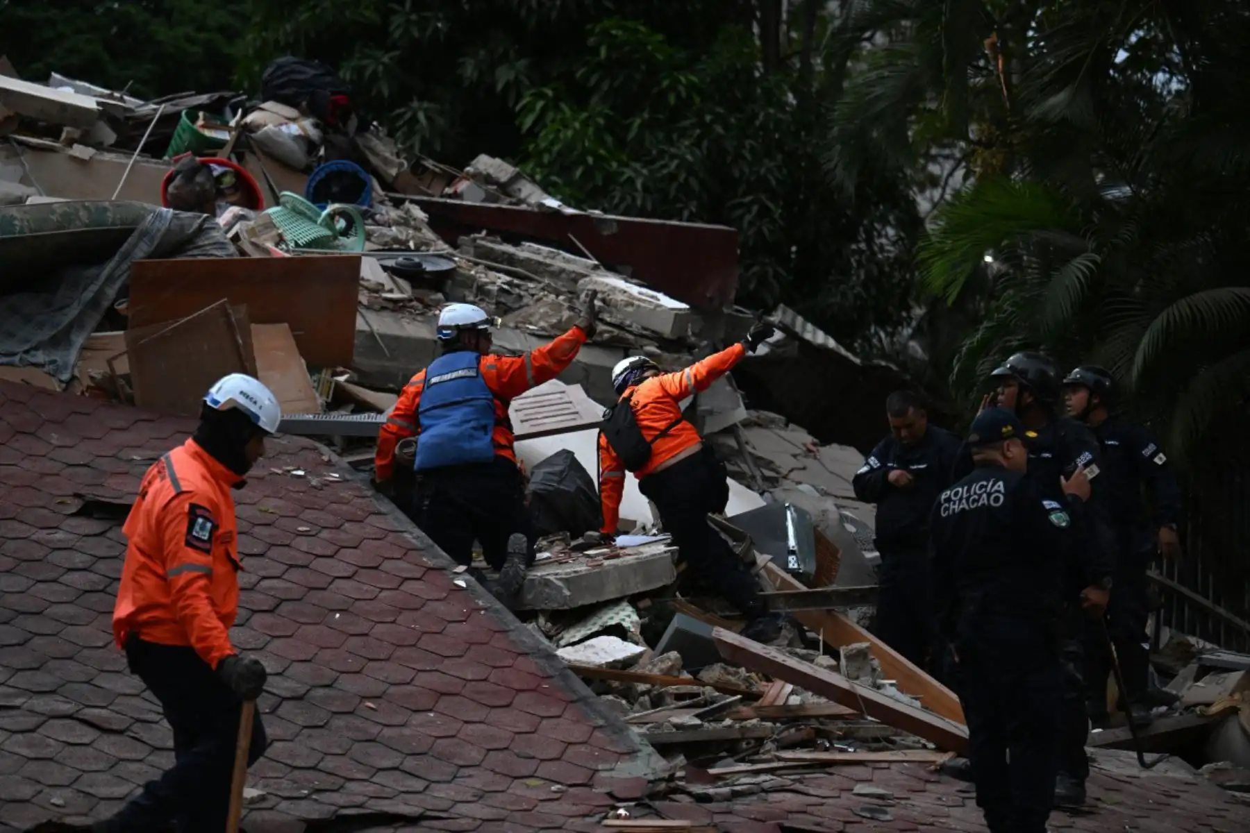 Los rescatistas buscan entre los restos de una estructura derrumbada mientras agentes de la policía municipal permanecen cerca tras el terremoto que sacudió Caracas. Un sismo de magnitud 7.1 sacudió Venezuela el miércoles, según informó el Servicio Geológico de Estados Unidos (USGS), provocando pánico en Caracas. Foto: ANDINA/AFP